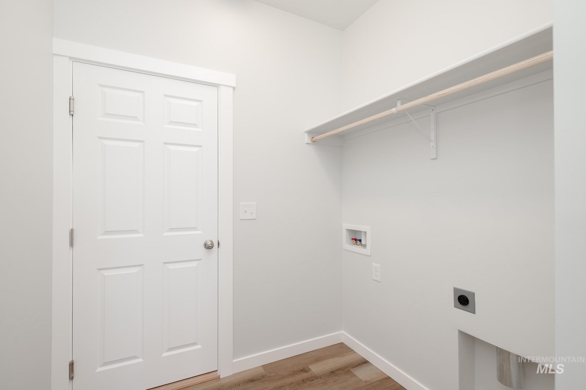 Laundry area with light wood finished floors, washer hookup, and electric dryer hookup