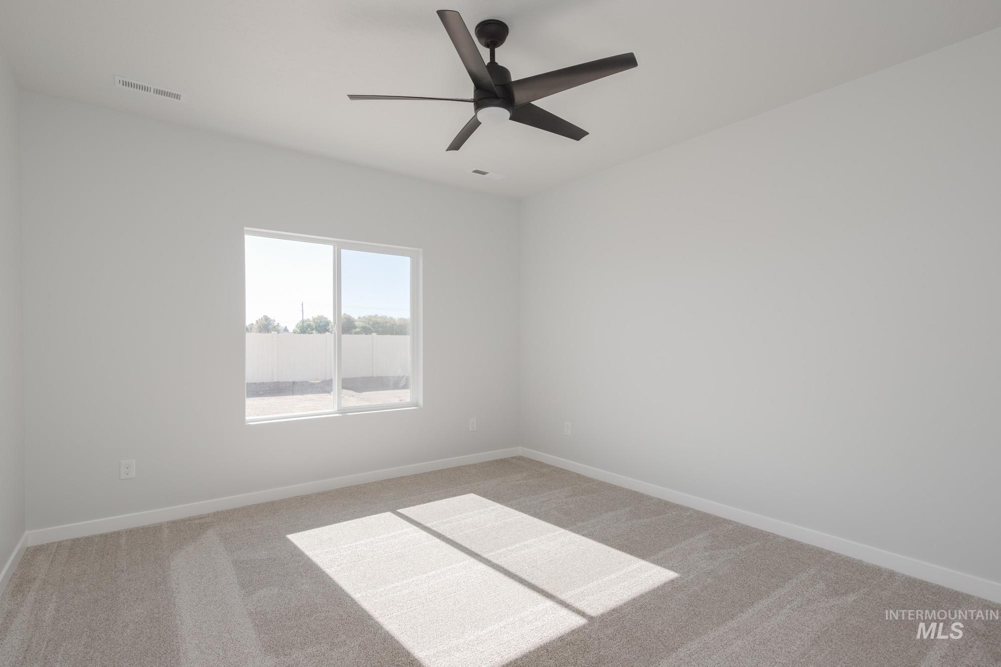 Empty room with light colored carpet and a ceiling fan
