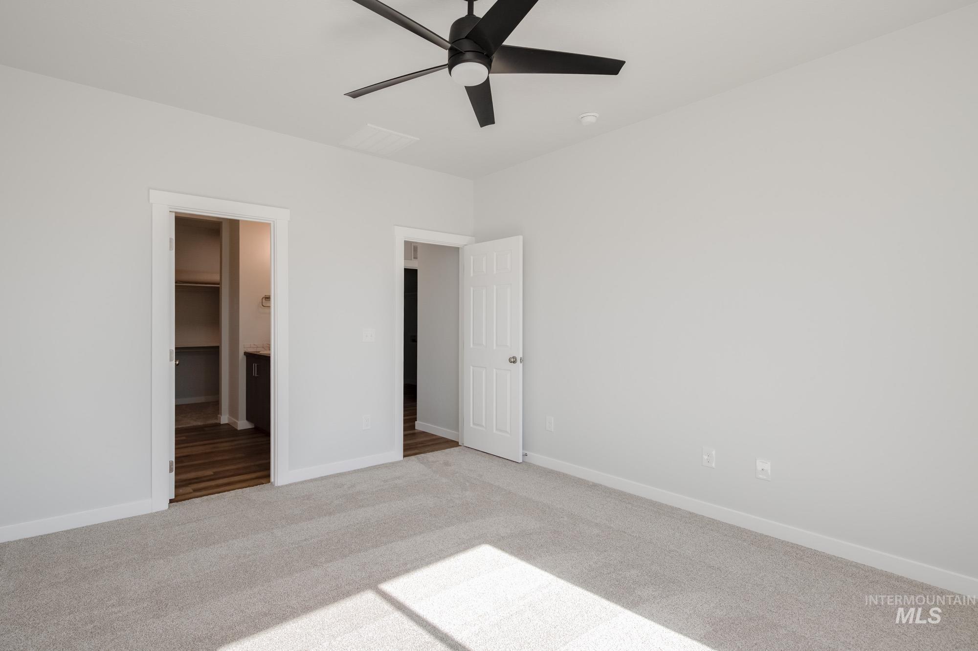 Unfurnished bedroom featuring carpet floors, ceiling fan, a spacious closet, and connected bathroom