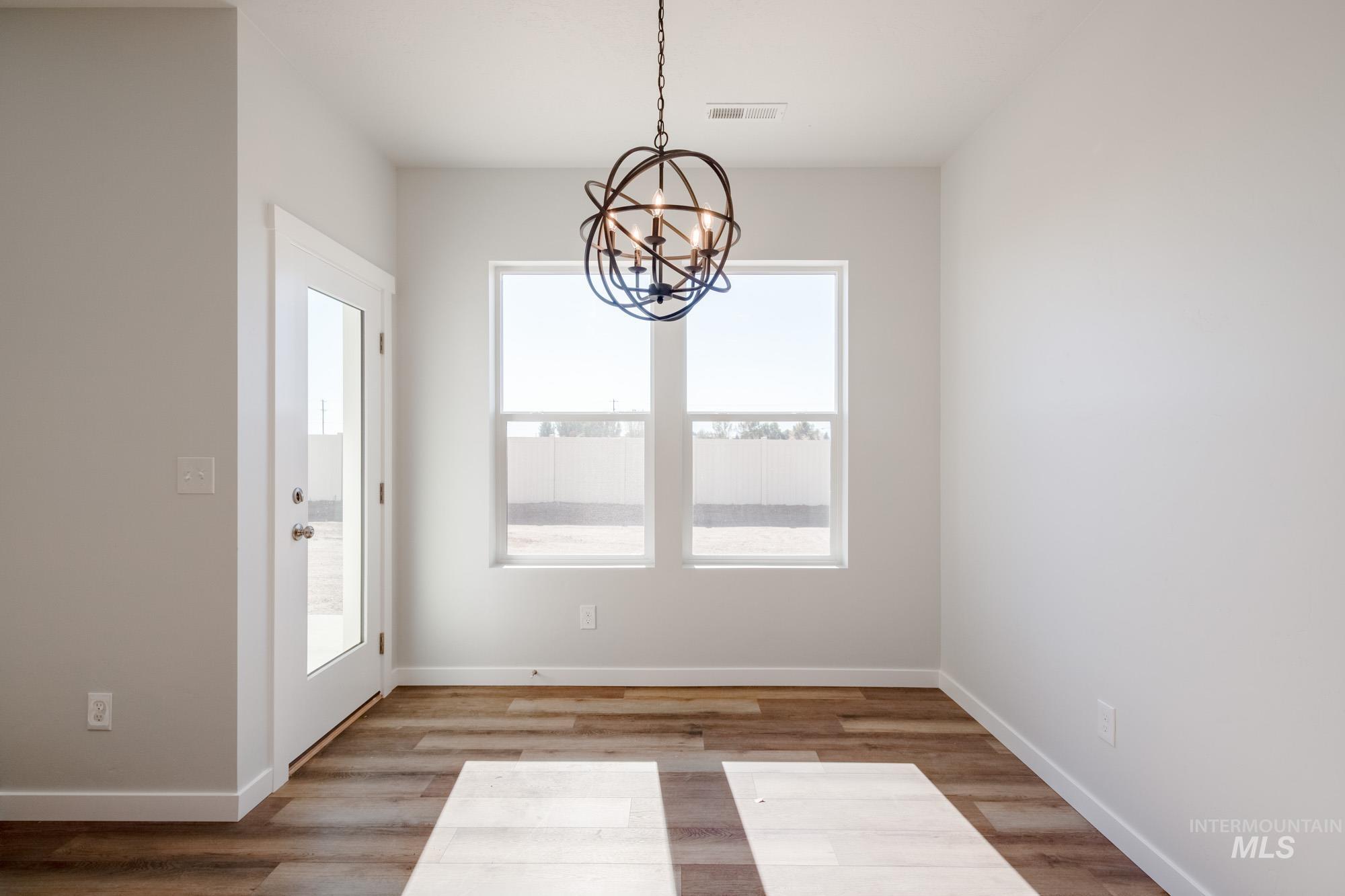 Unfurnished dining area featuring light wood-type flooring and a chandelier
