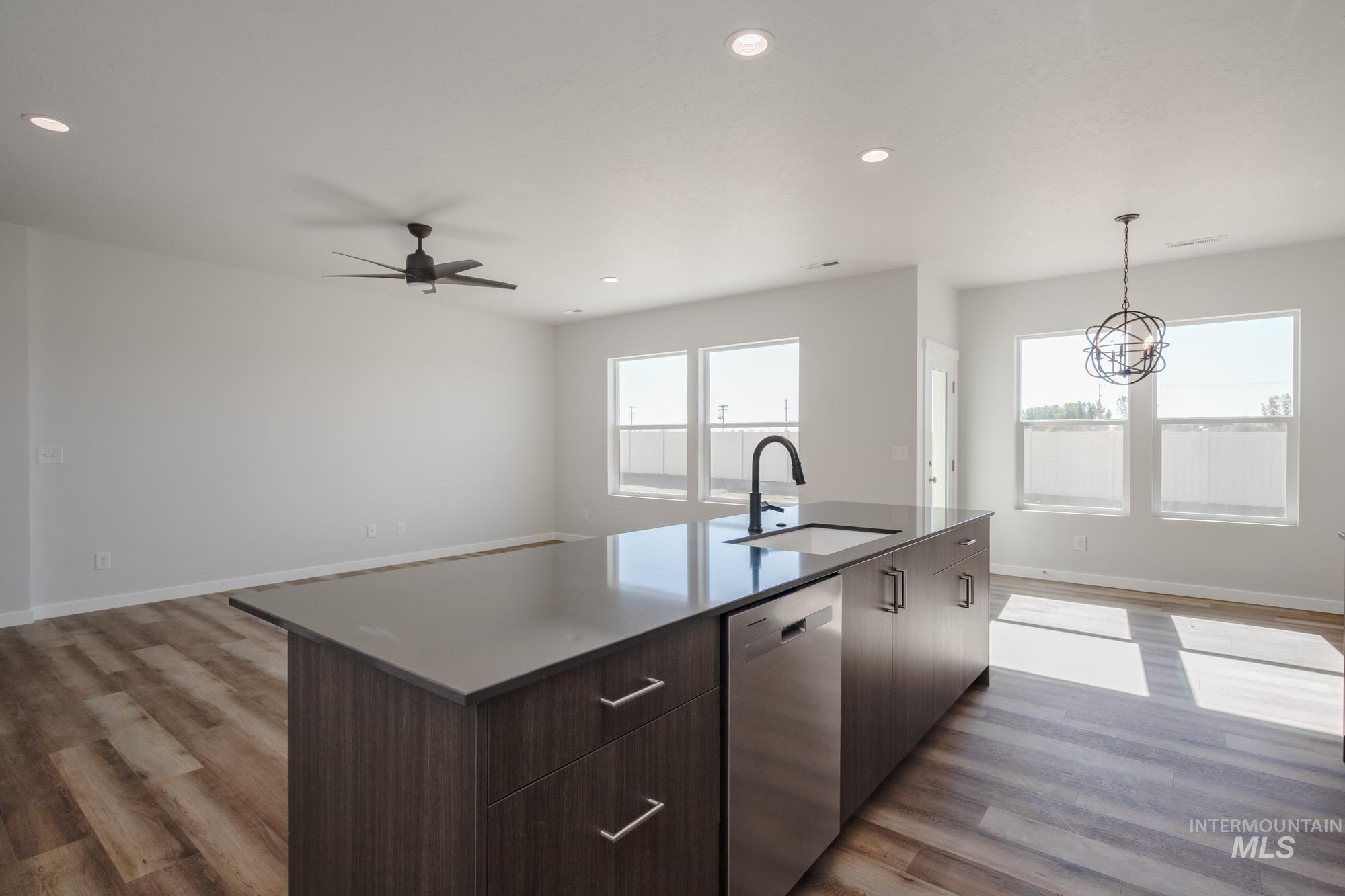 Kitchen with open floor plan, dark brown cabinetry, recessed lighting, dishwasher, and light wood-type flooring