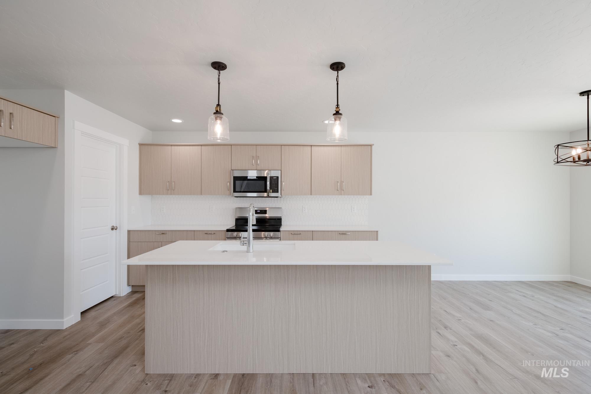 Kitchen featuring pendant lighting, stainless steel appliances, light wood finished floors, backsplash, and recessed lighting