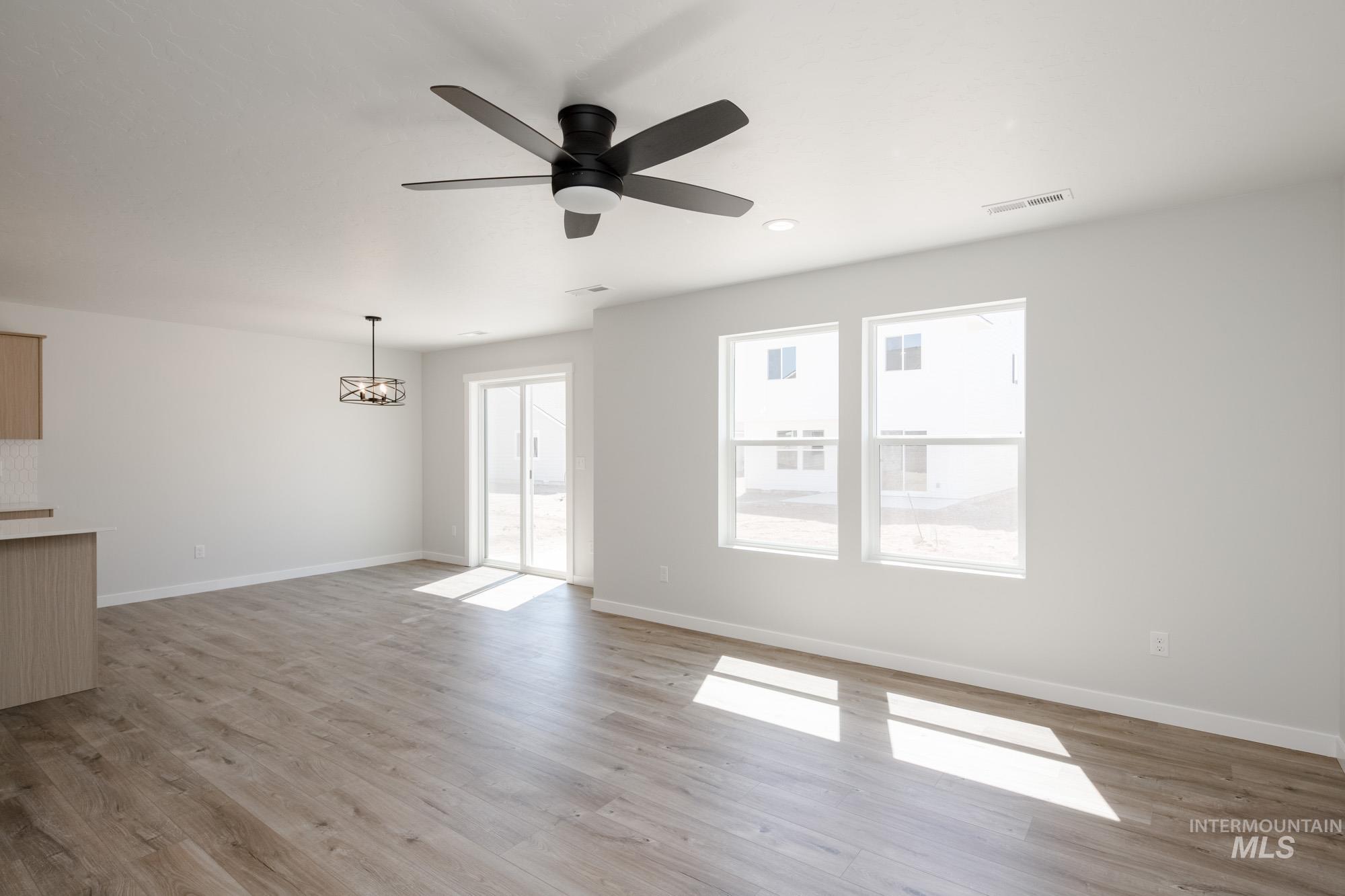 Unfurnished living room with light wood finished floors, ceiling fan, a chandelier, and recessed lighting