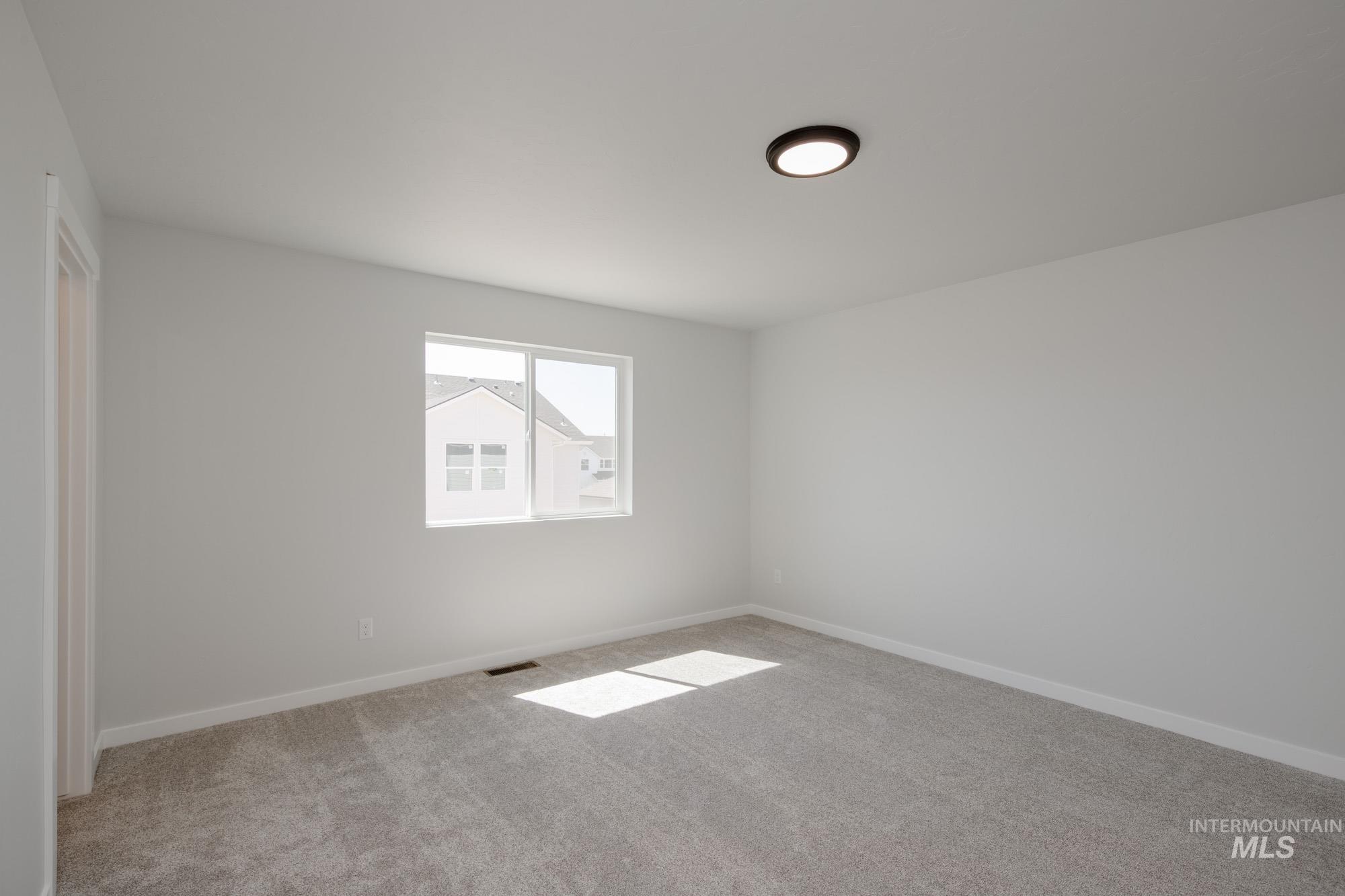 Spare room with light colored carpet and baseboards