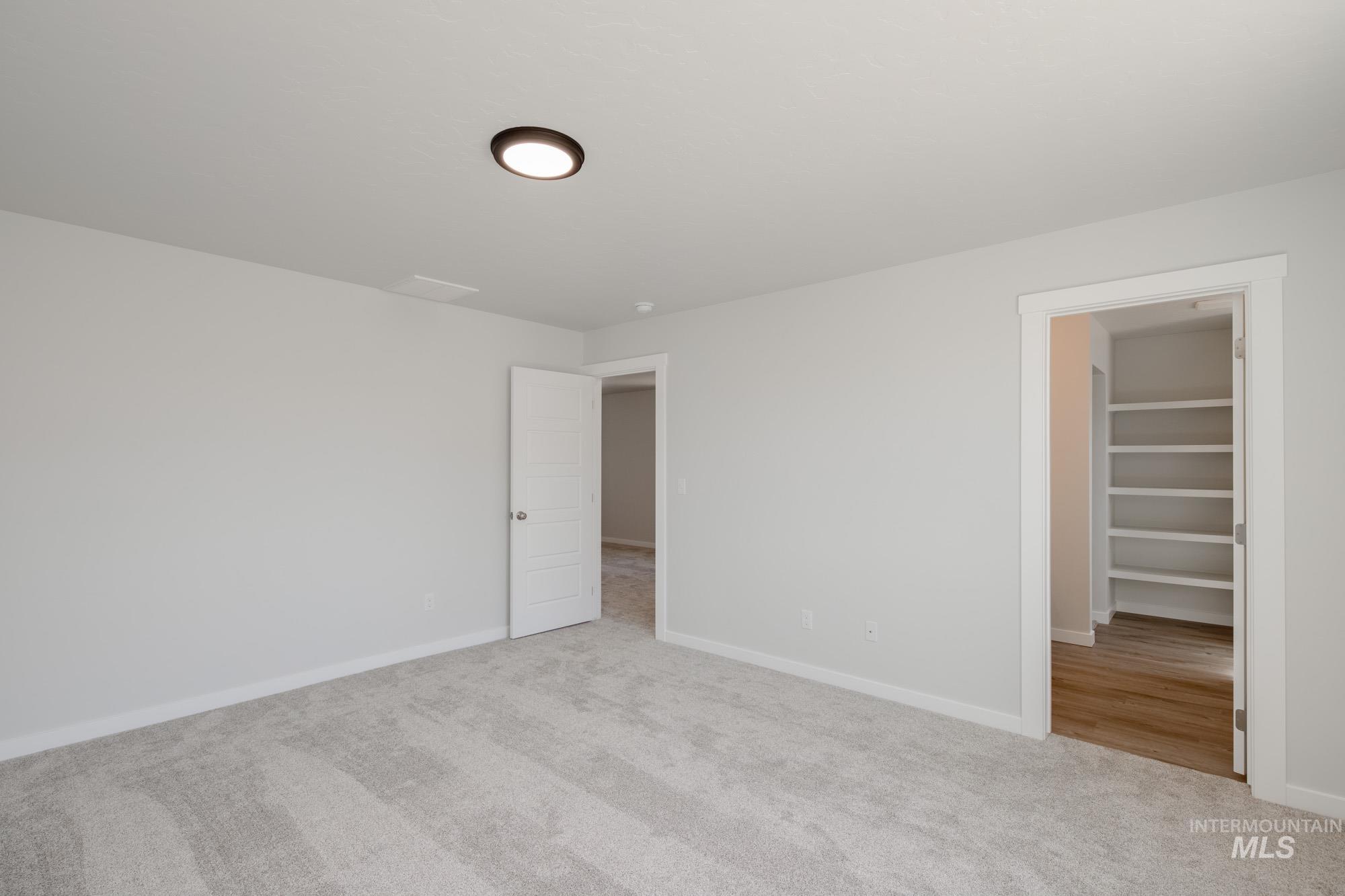 Unfurnished bedroom with light carpet and a spacious closet