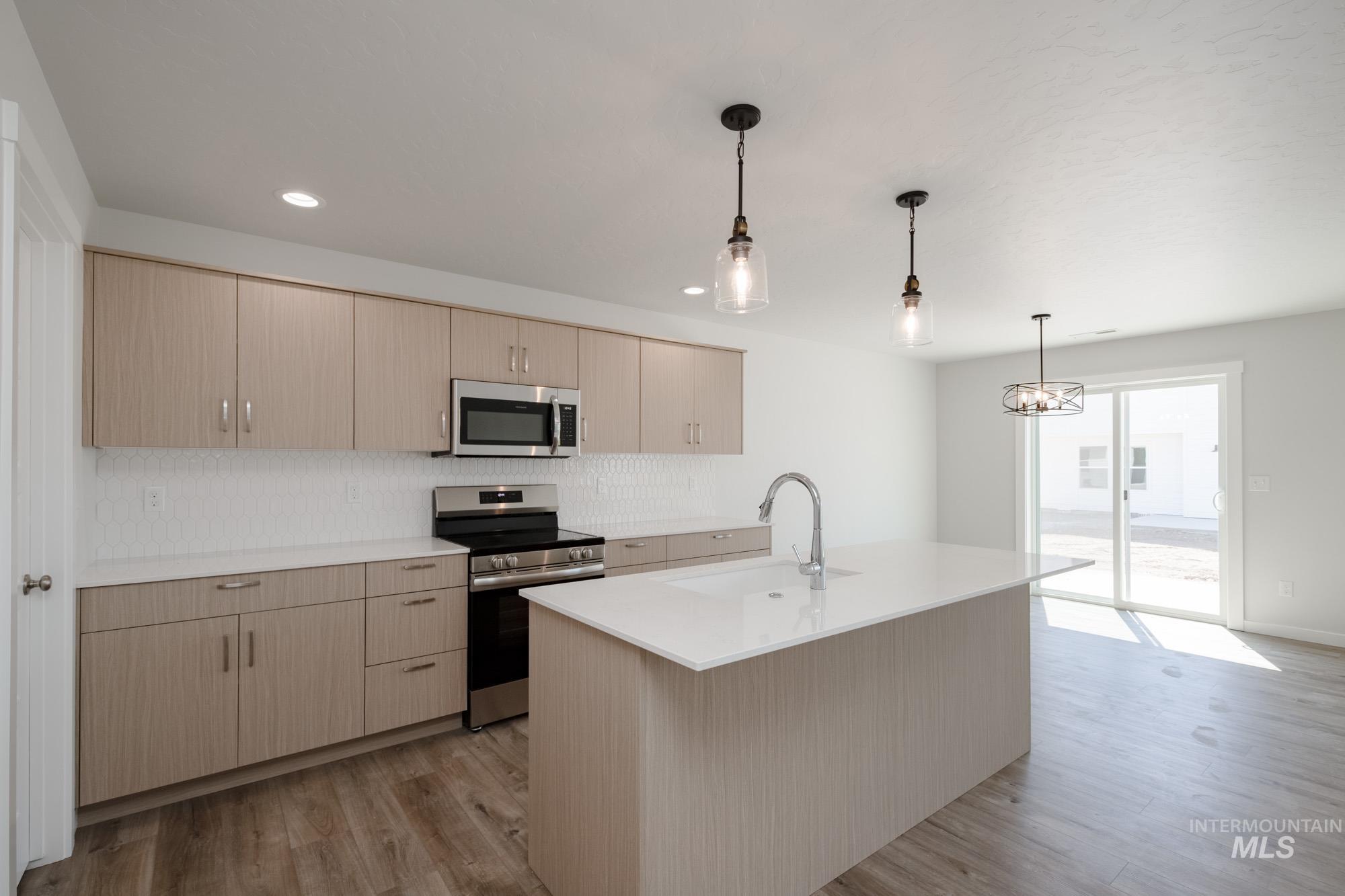 Kitchen featuring appliances with stainless steel finishes, decorative light fixtures, backsplash, light wood finished floors, and recessed lighting