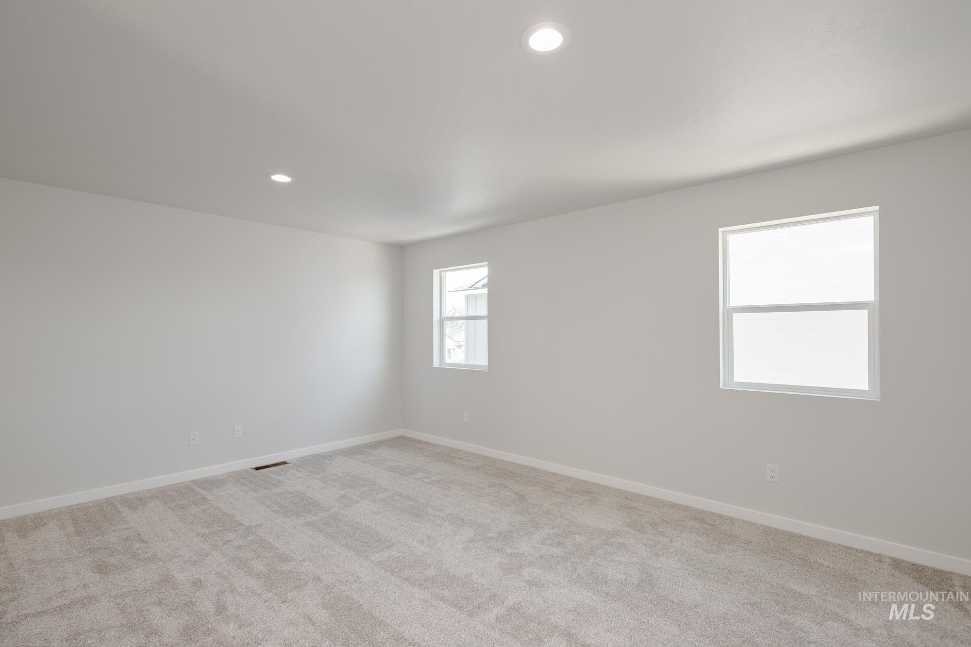 Empty room with light colored carpet and recessed lighting