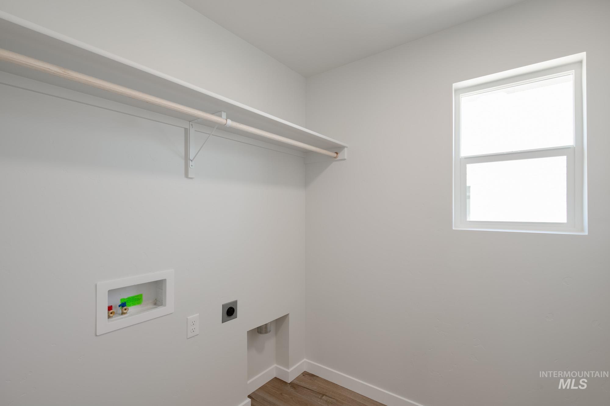 Laundry room with light wood-style floors, hookup for an electric dryer, and washer hookup