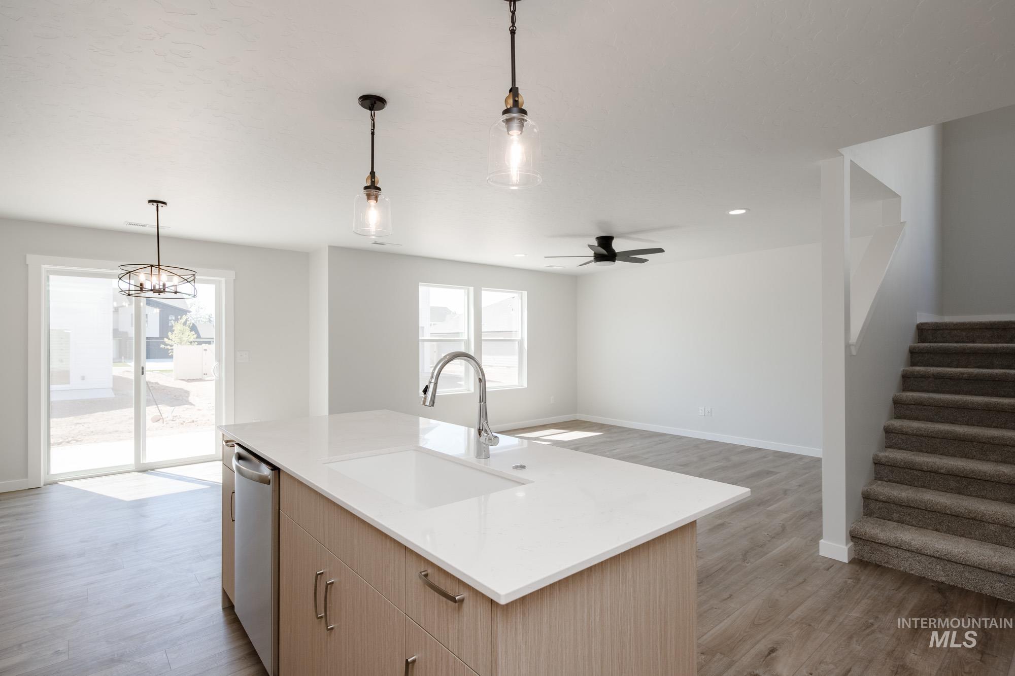Kitchen with decorative light fixtures, ceiling fan, light wood-style floors, light stone counters, and recessed lighting