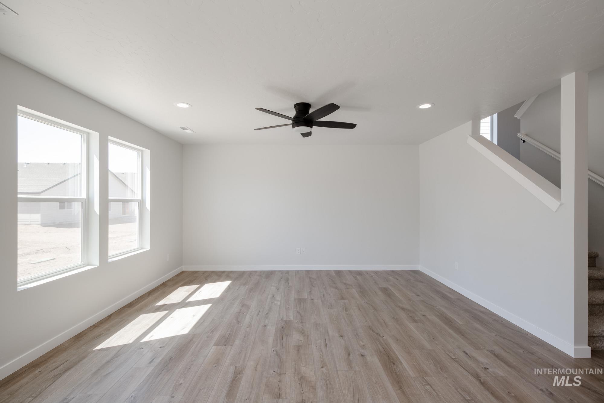Unfurnished living room featuring light wood-style flooring, recessed lighting, stairway, and ceiling fan