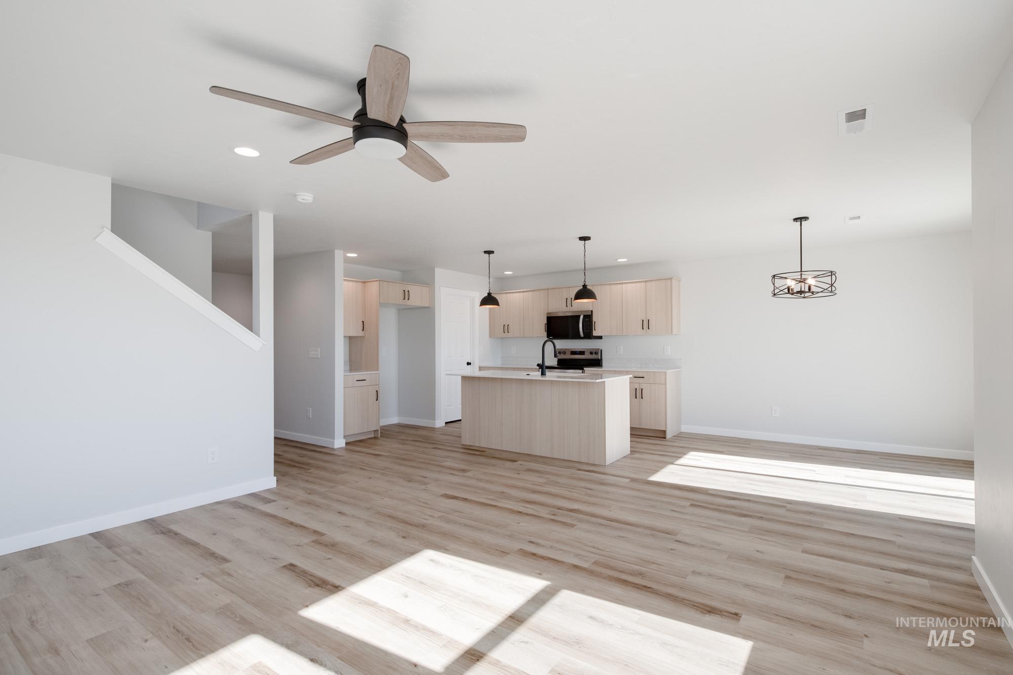Unfurnished living room featuring light wood finished floors, ceiling fan, and recessed lighting