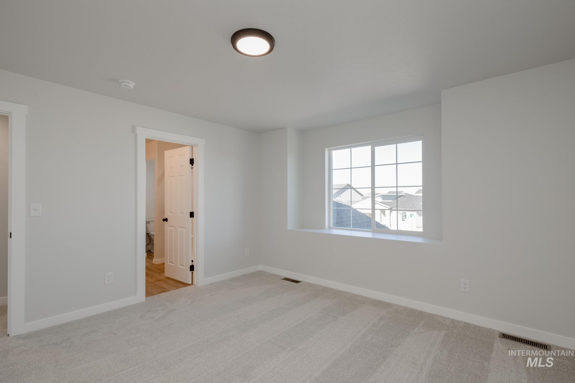 Spare room with light colored carpet and baseboards