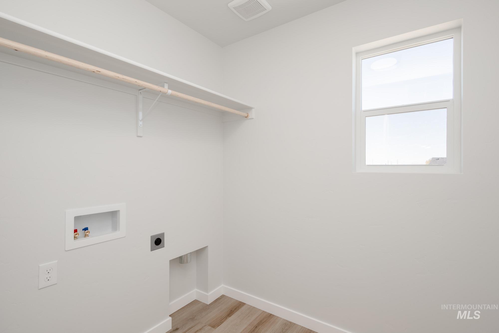 Laundry room with light wood-type flooring, hookup for a washing machine, and hookup for an electric dryer
