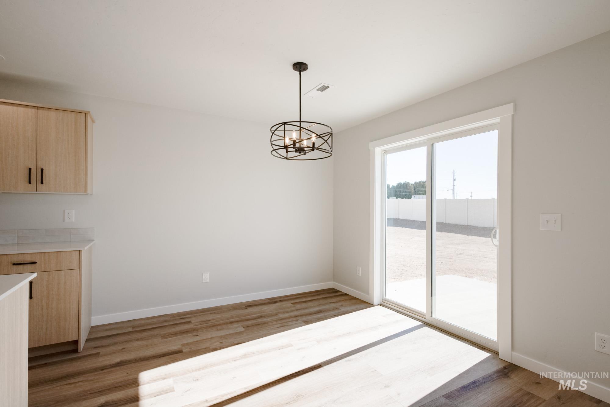 Unfurnished dining area with light wood finished floors and a chandelier