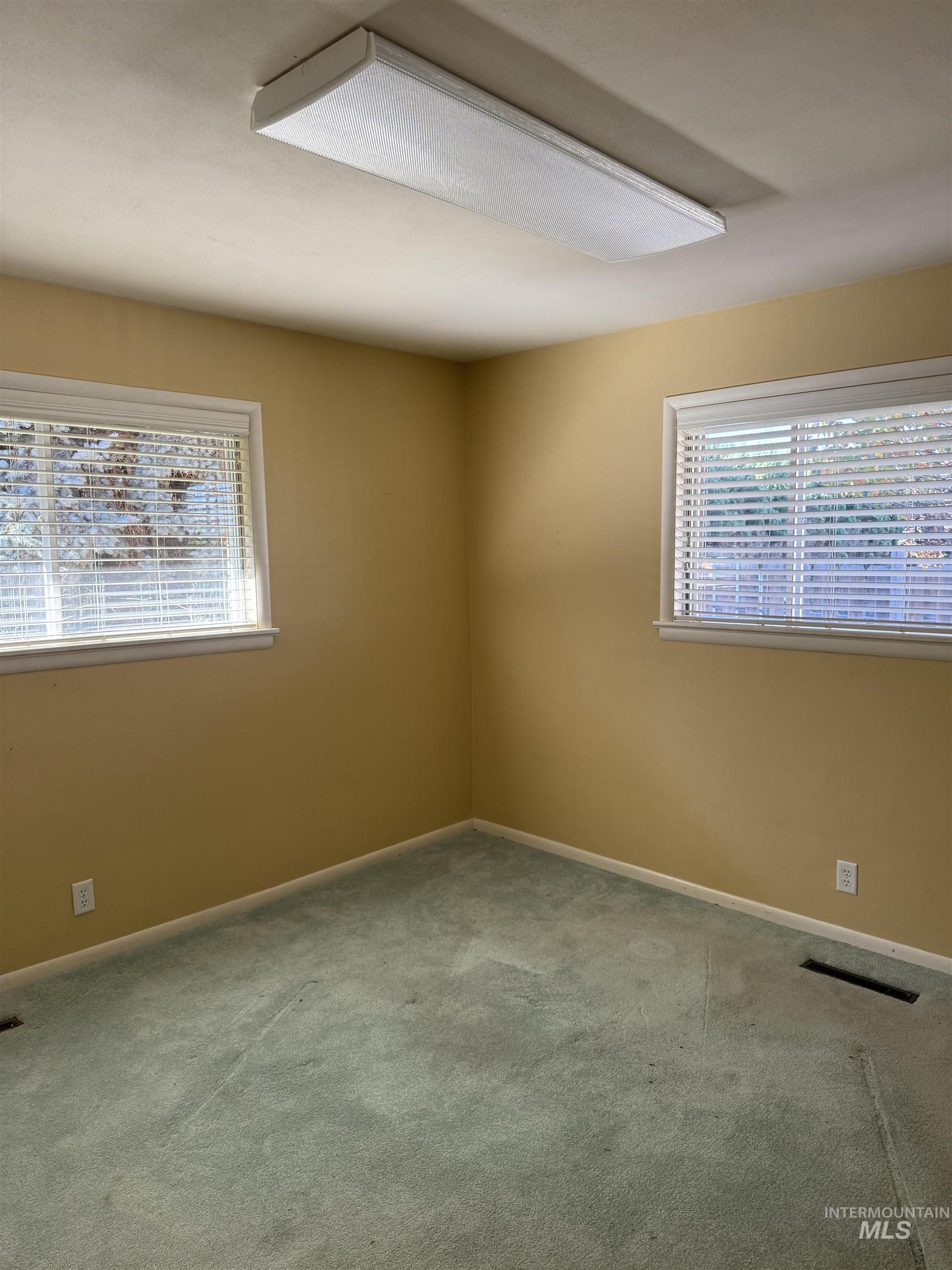 Carpeted spare room featuring baseboards