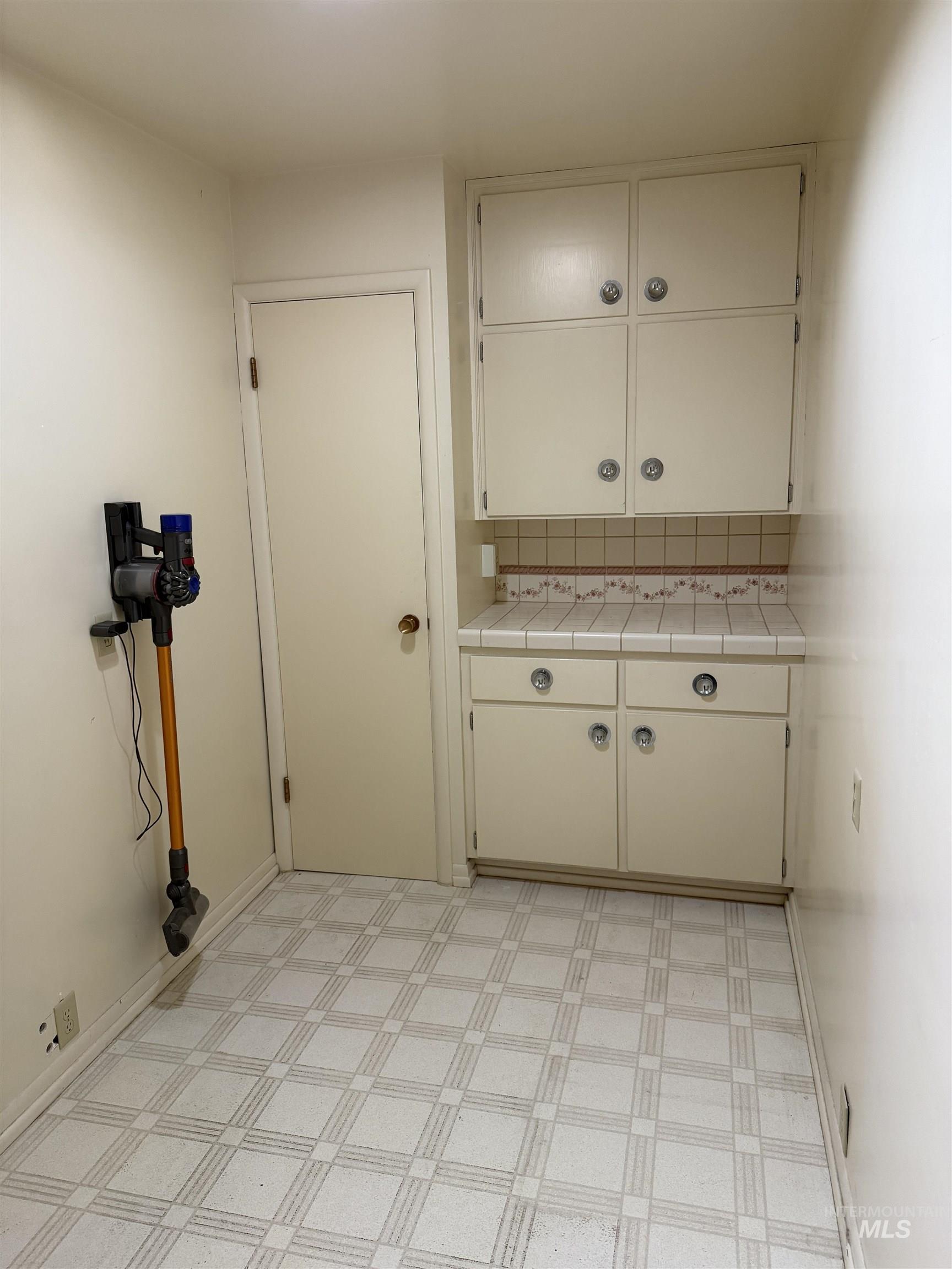 Laundry area featuring light flooring and baseboards