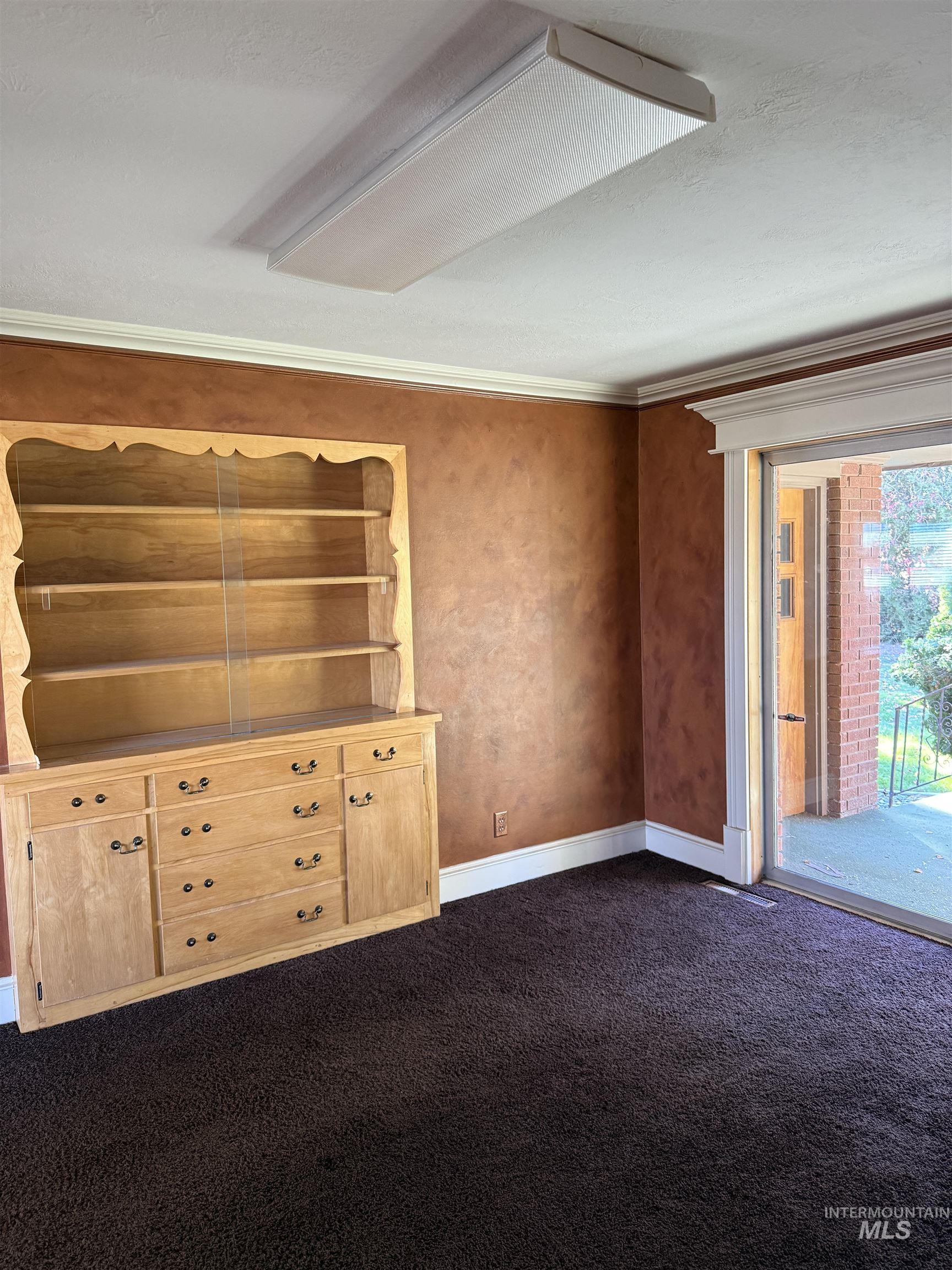 Unfurnished room featuring dark carpet and ornamental molding