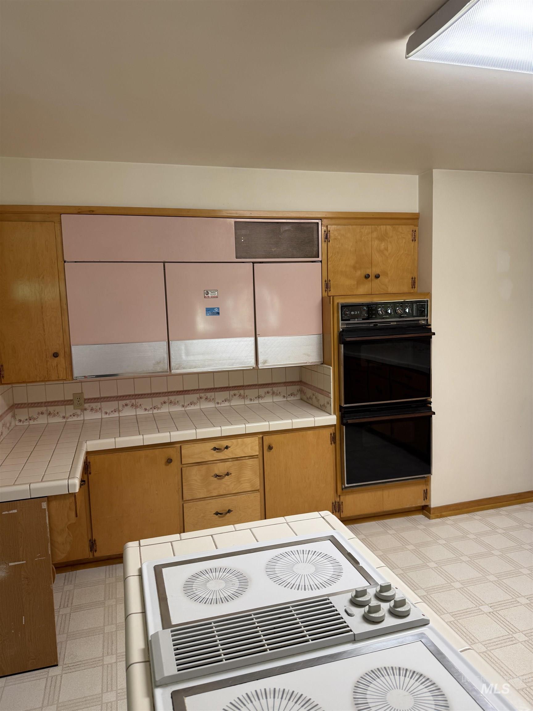 Kitchen with light flooring, brown cabinetry, and tile countertops