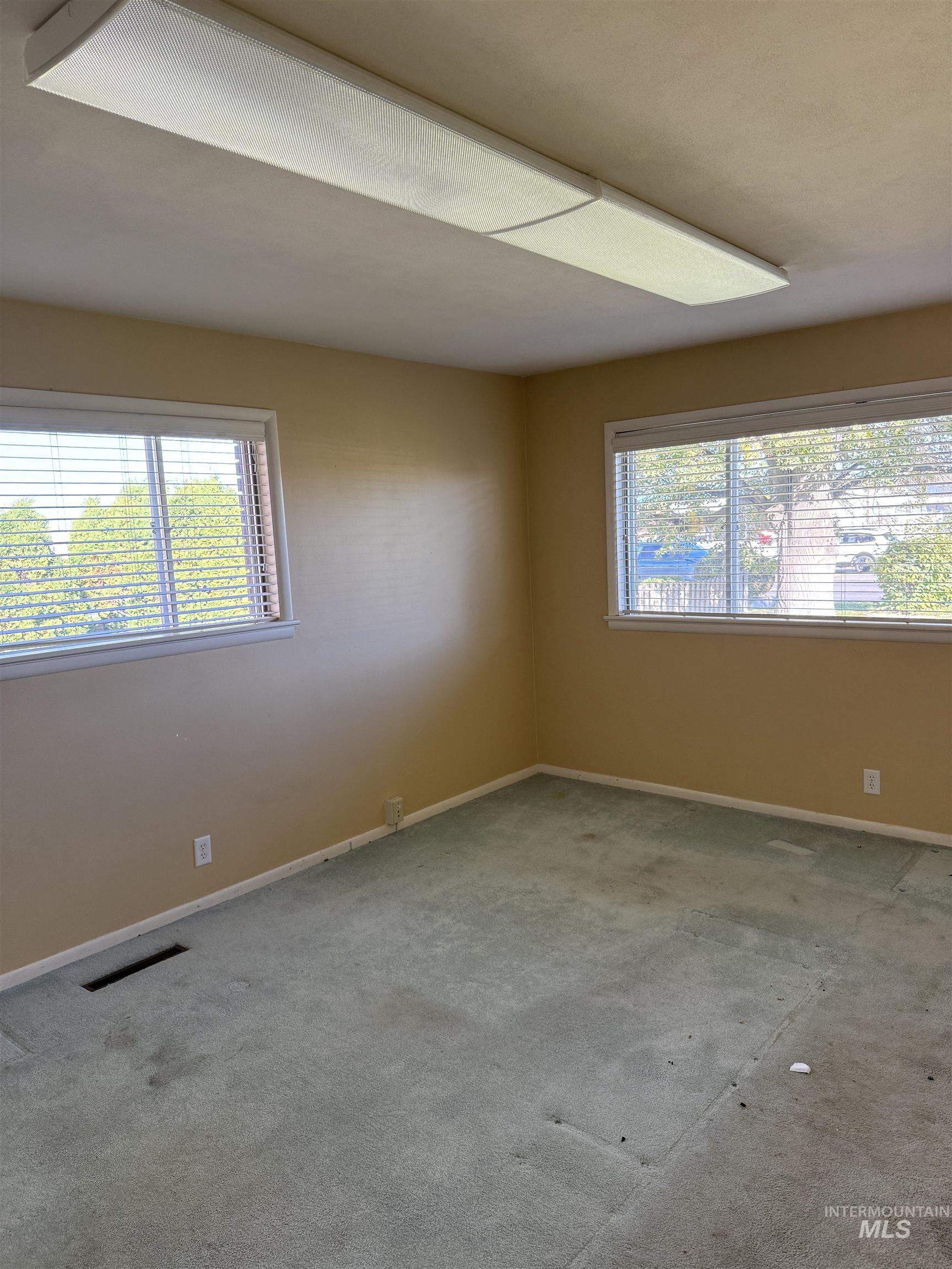 Carpeted spare room featuring healthy amount of natural light