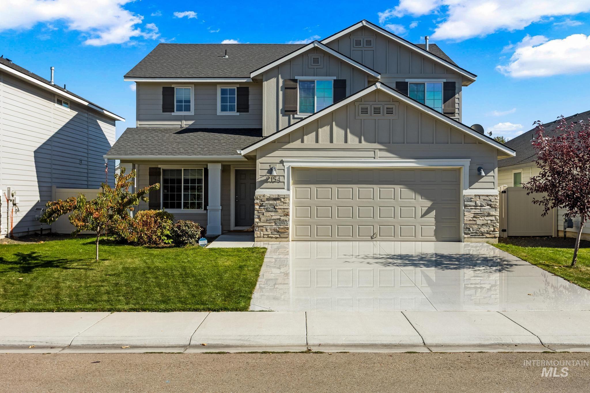 Craftsman-style home with stone siding, board and batten siding, driveway, roof with shingles, and a garage