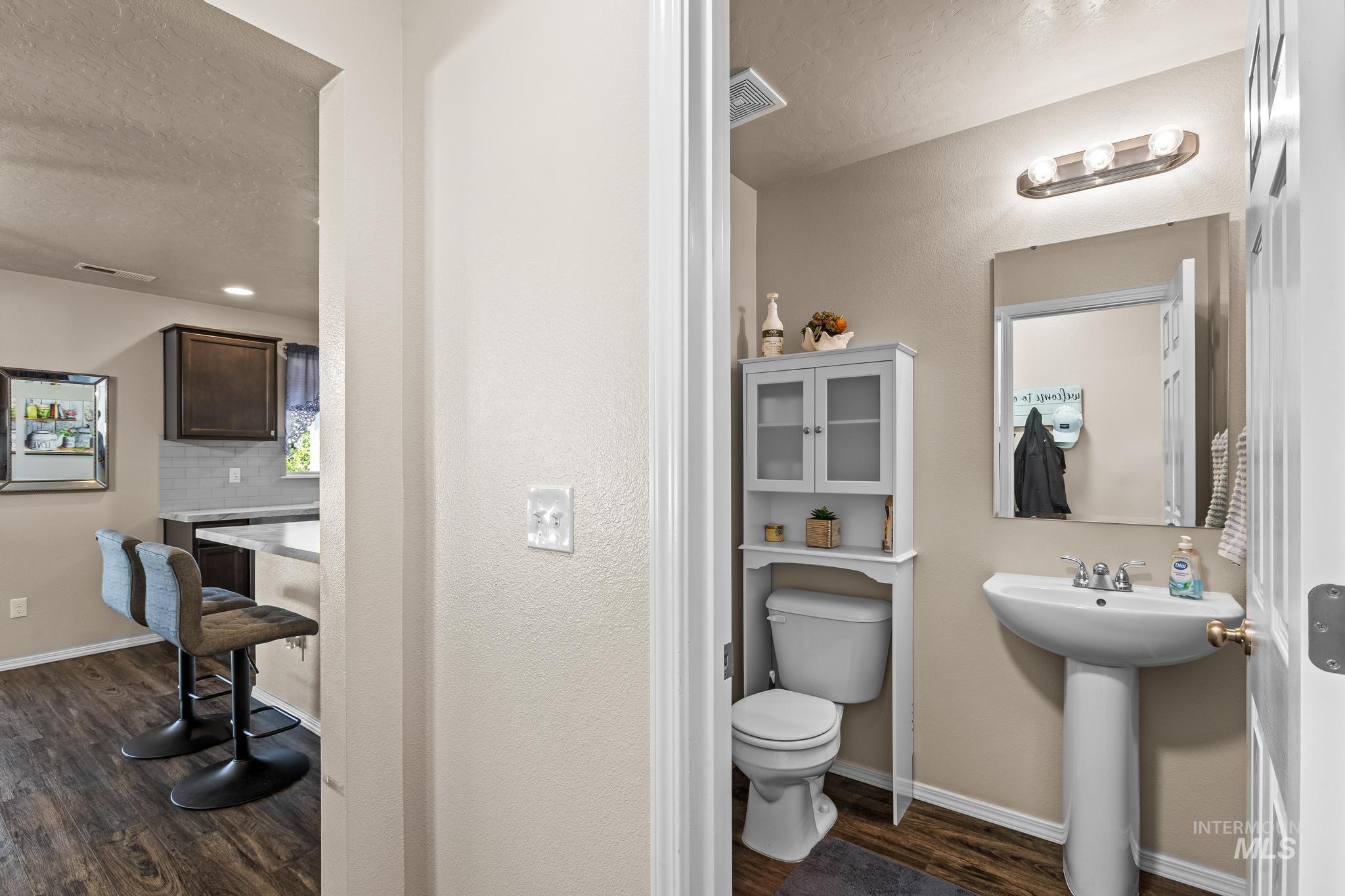 Bathroom featuring dark wood finished floors, tasteful backsplash, and a textured ceiling