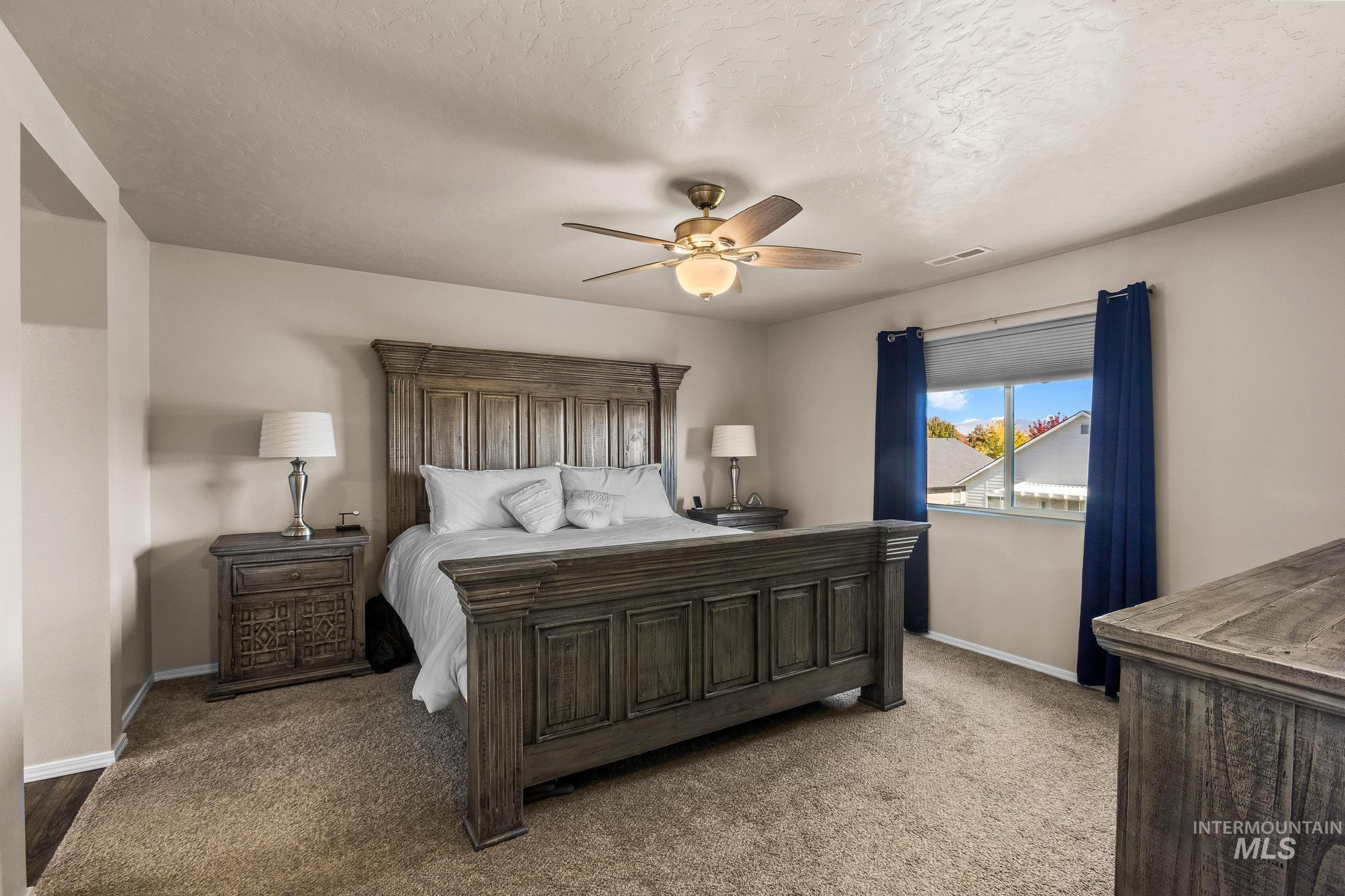 Carpeted bedroom featuring a textured ceiling and ceiling fan
