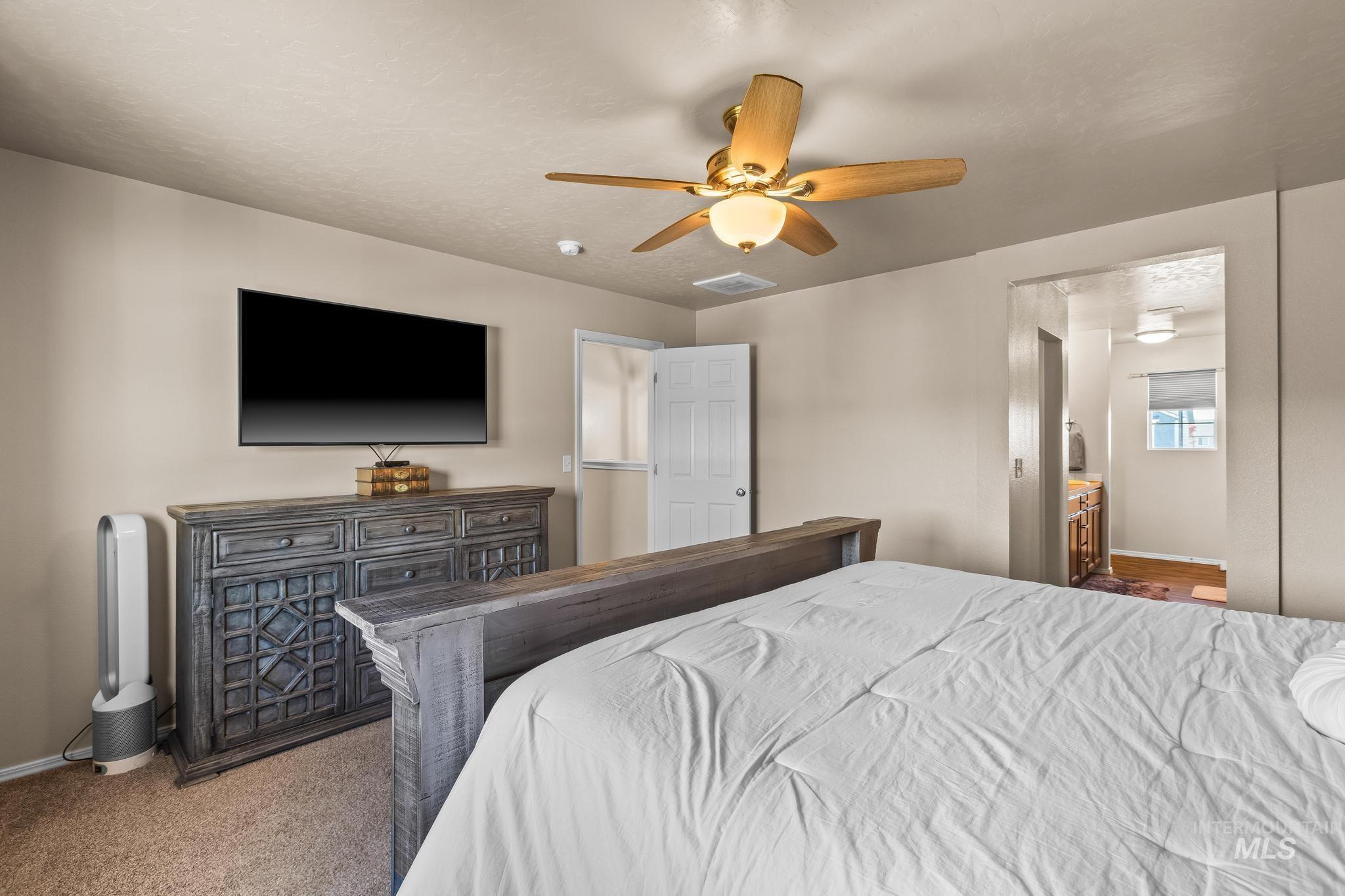 Bedroom featuring light colored carpet, ensuite bathroom, a ceiling fan, and a textured ceiling