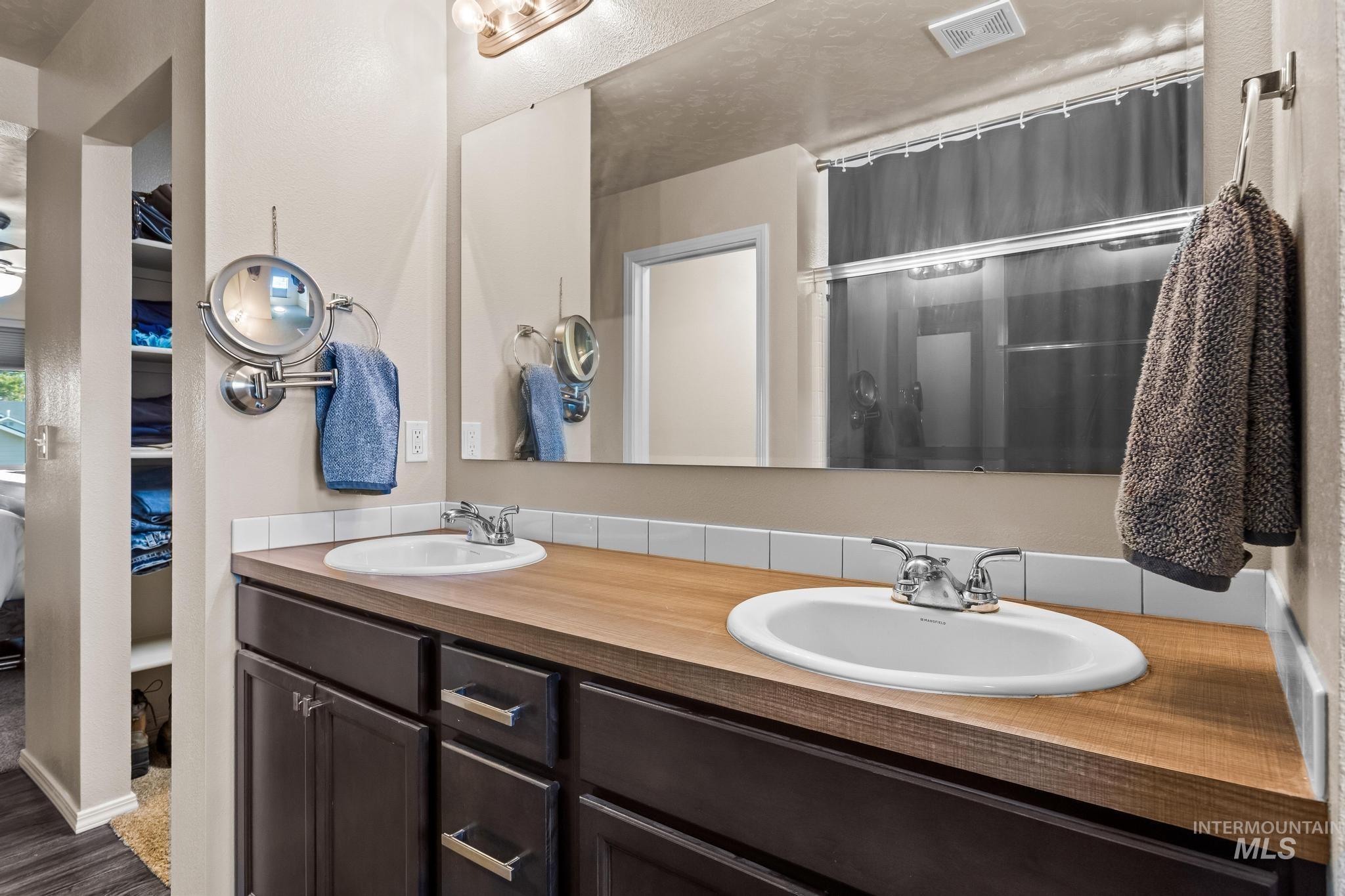 Bathroom featuring a shower with shower curtain and double vanity