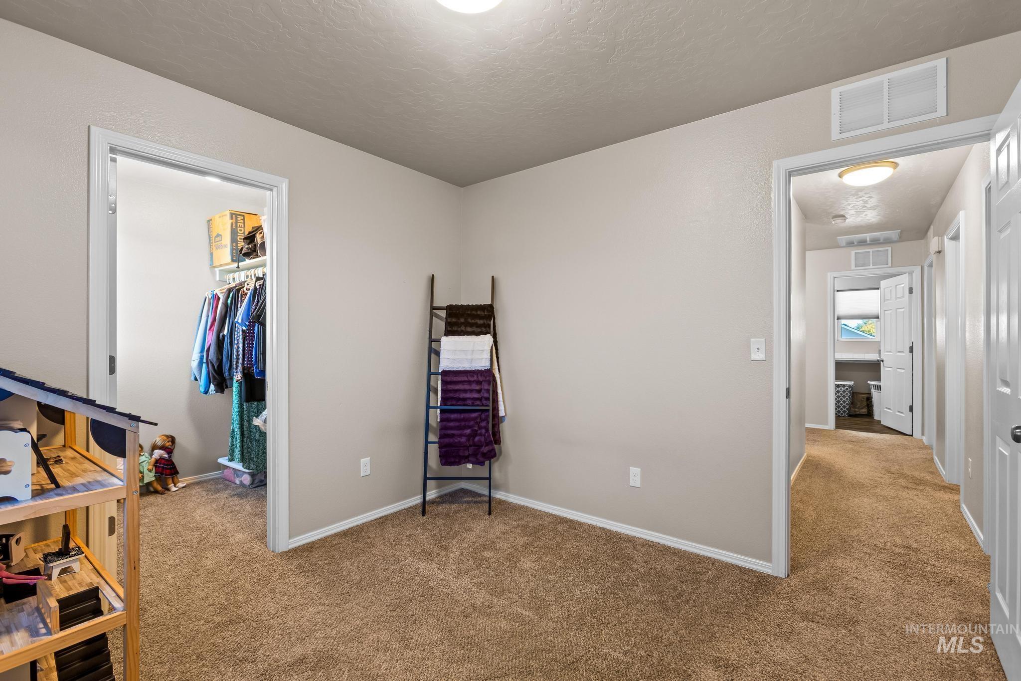 Bedroom featuring light carpet, a spacious closet, and a textured ceiling