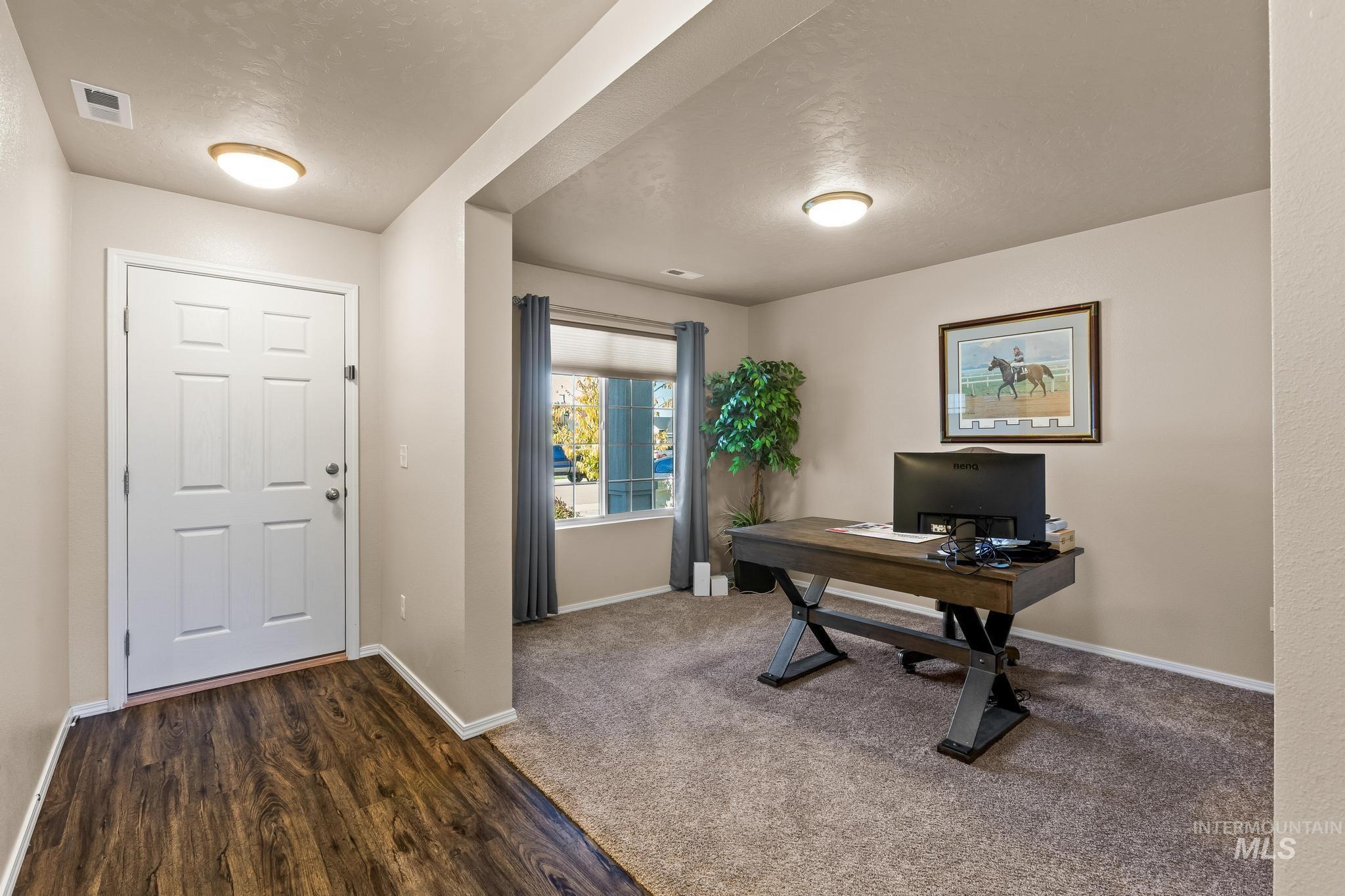 Office area with dark wood-type flooring, a textured ceiling, and dark carpet