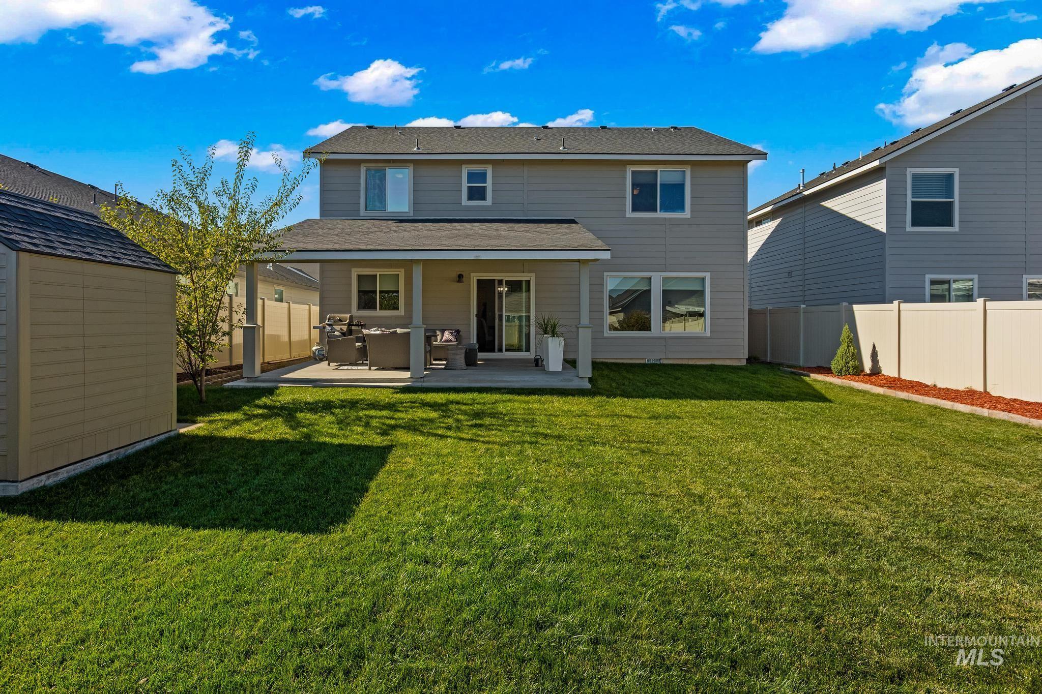 Back of house with a patio area, a fenced backyard, a storage shed, and a shingled roof