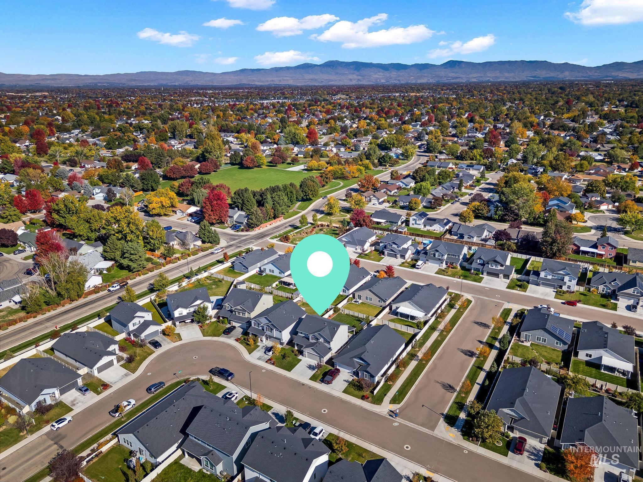 Aerial view of property and surrounding area with nearby suburban area and a mountain backdrop