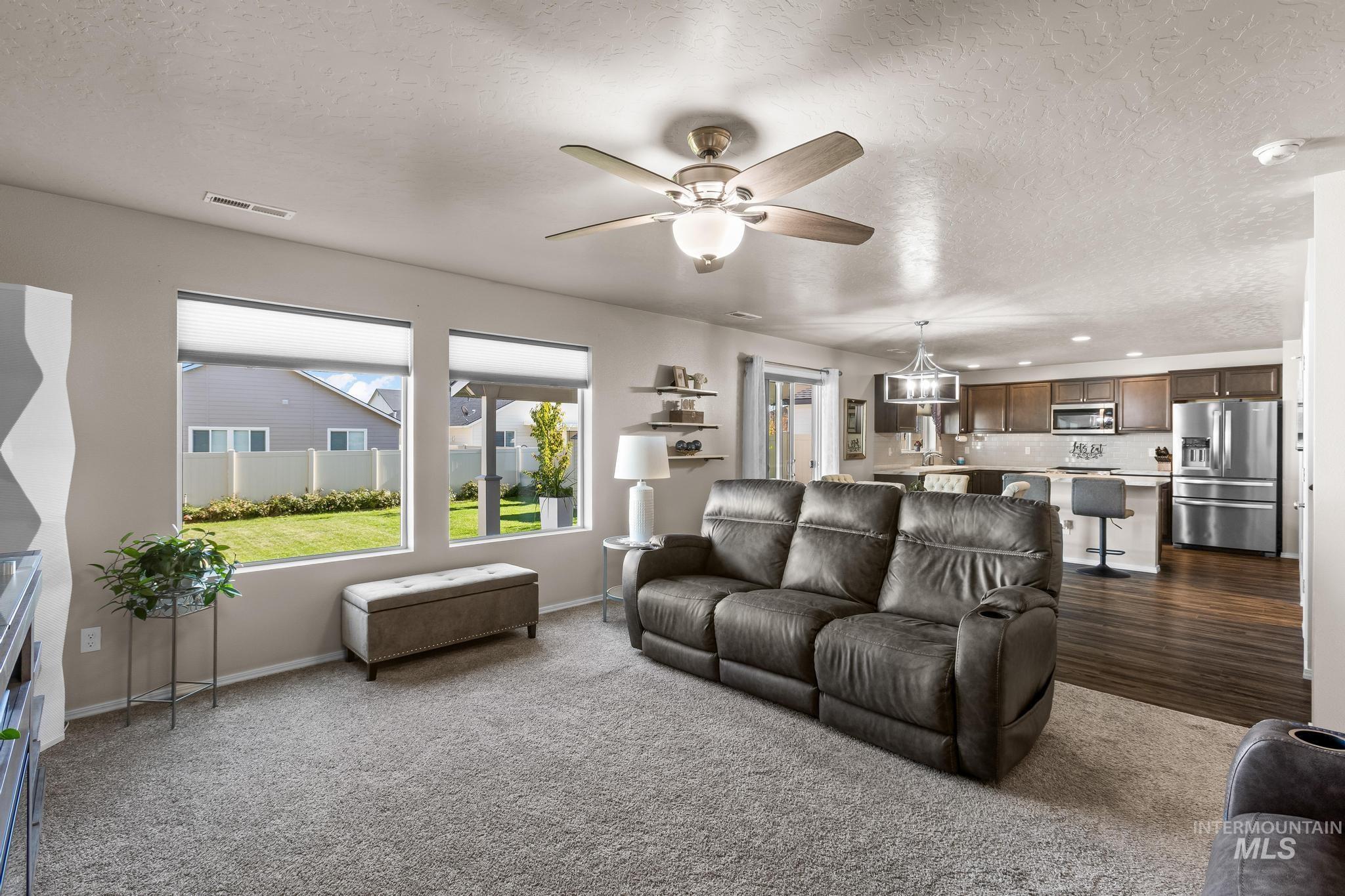 Living room featuring a textured ceiling, dark colored carpet, and ceiling fan