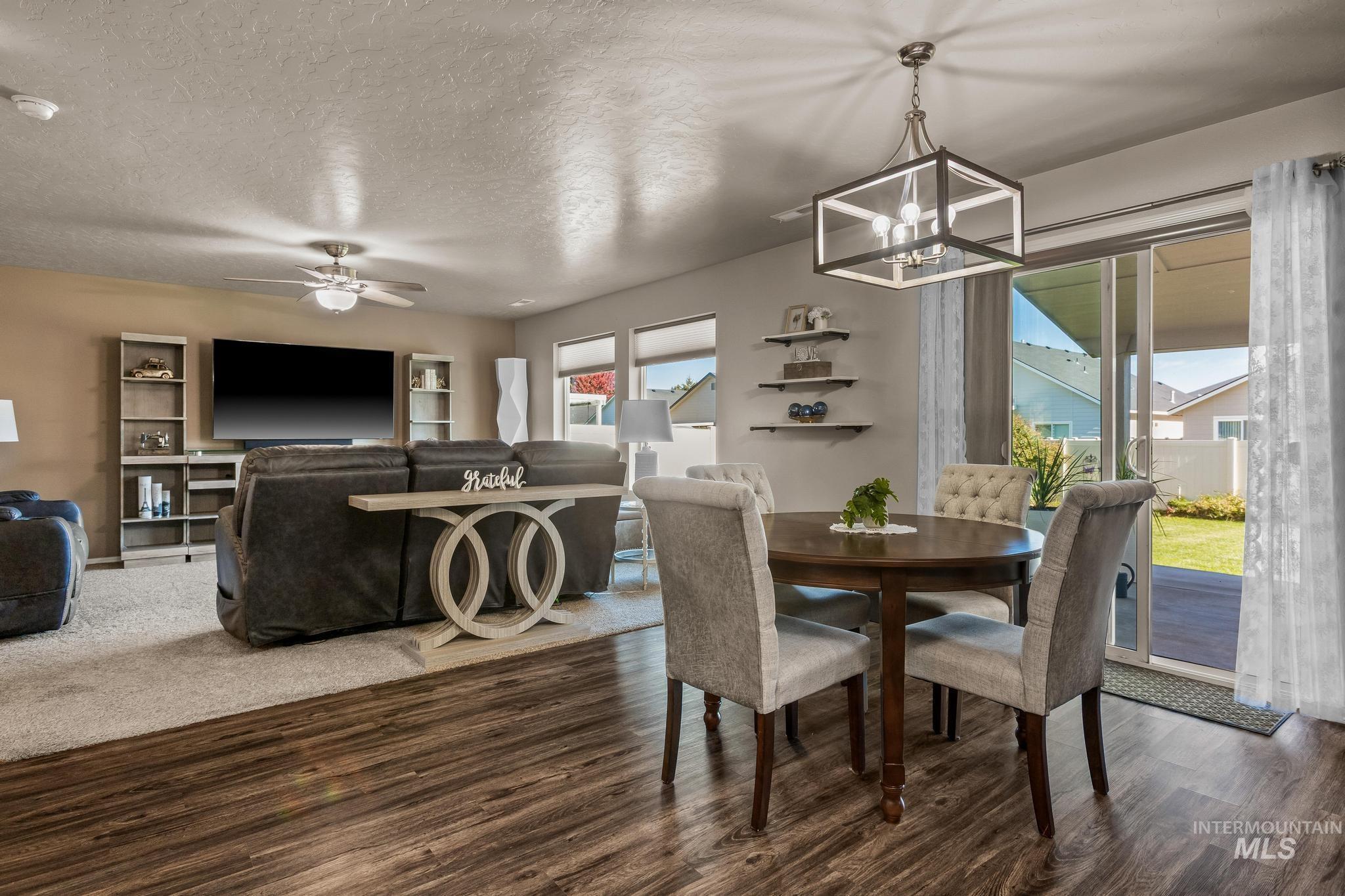 Dining area with a textured ceiling, dark wood finished floors, a chandelier, and a ceiling fan