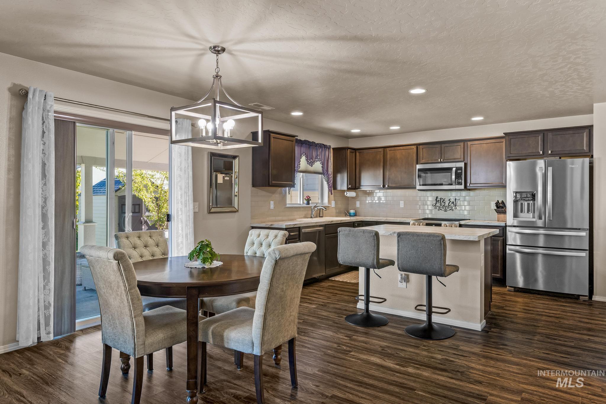 Dining room with dark wood finished floors, a chandelier, recessed lighting, and a textured ceiling