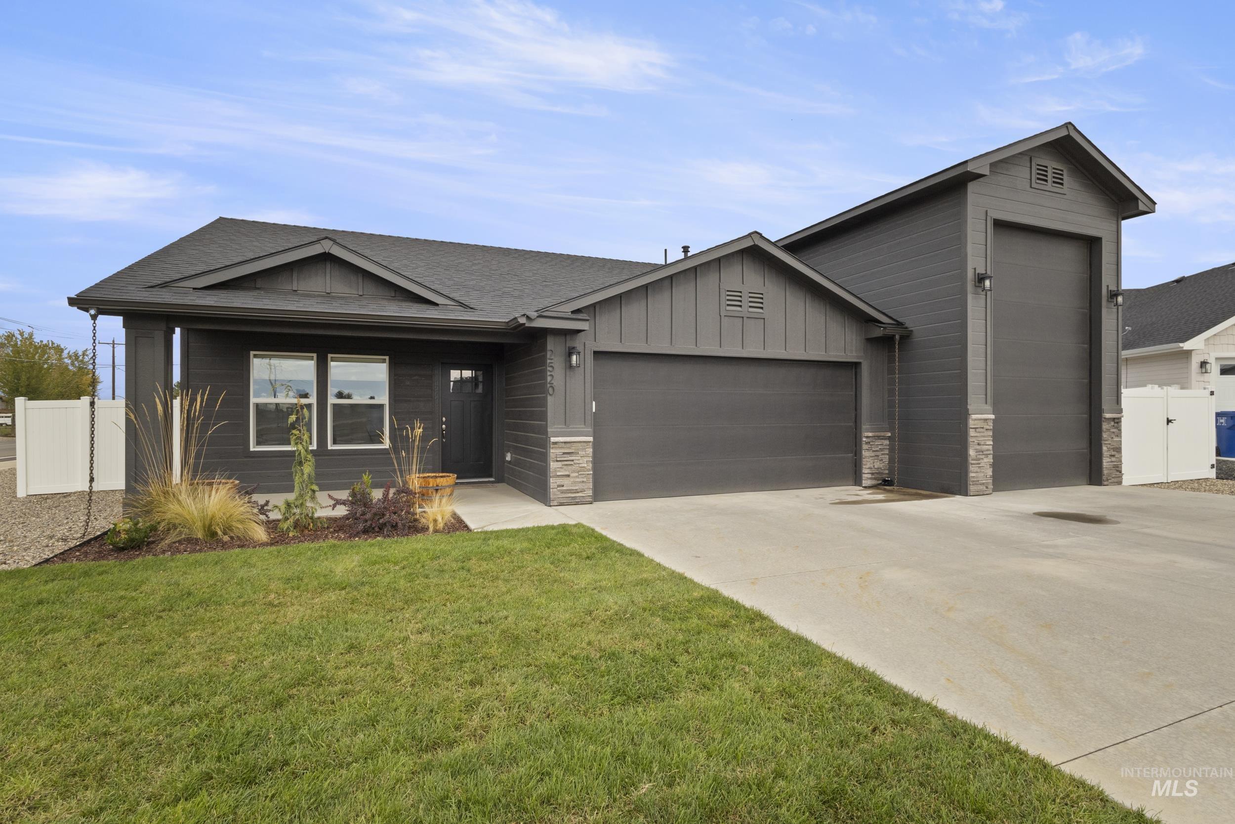 View of front of house featuring board and batten siding, an attached garage, concrete driveway, and stone siding