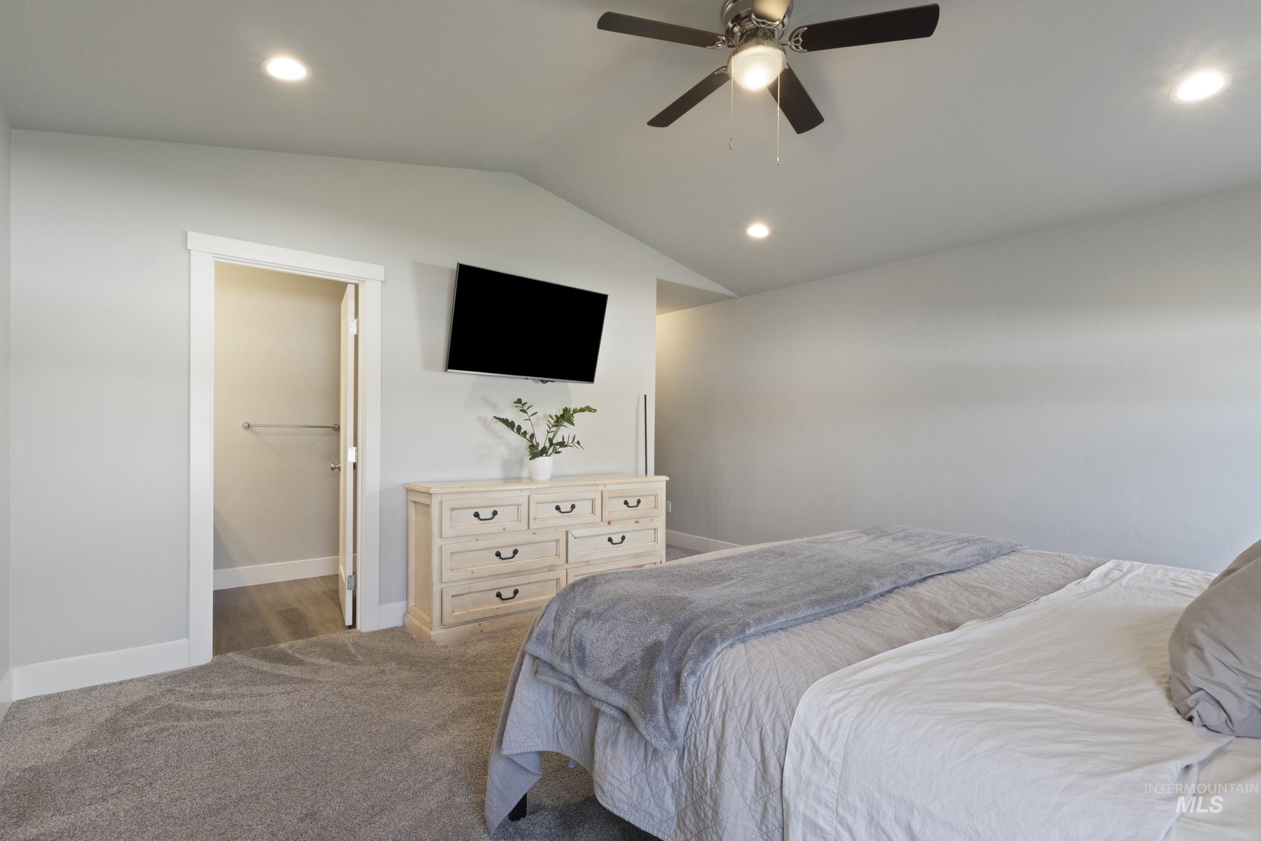 Bedroom featuring lofted ceiling, recessed lighting, ceiling fan, ensuite bath, and carpet flooring