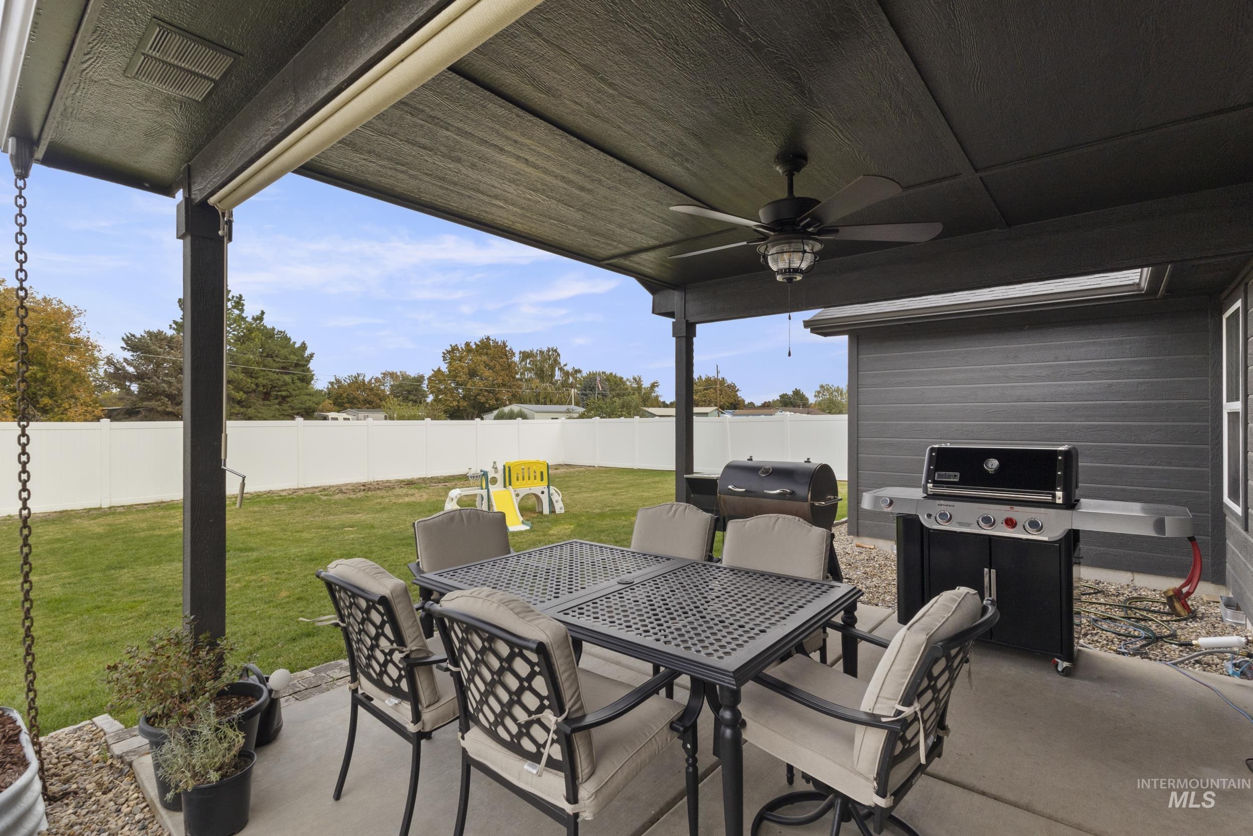 Fenced backyard featuring a patio, outdoor dining space, ceiling fan, and area for grilling