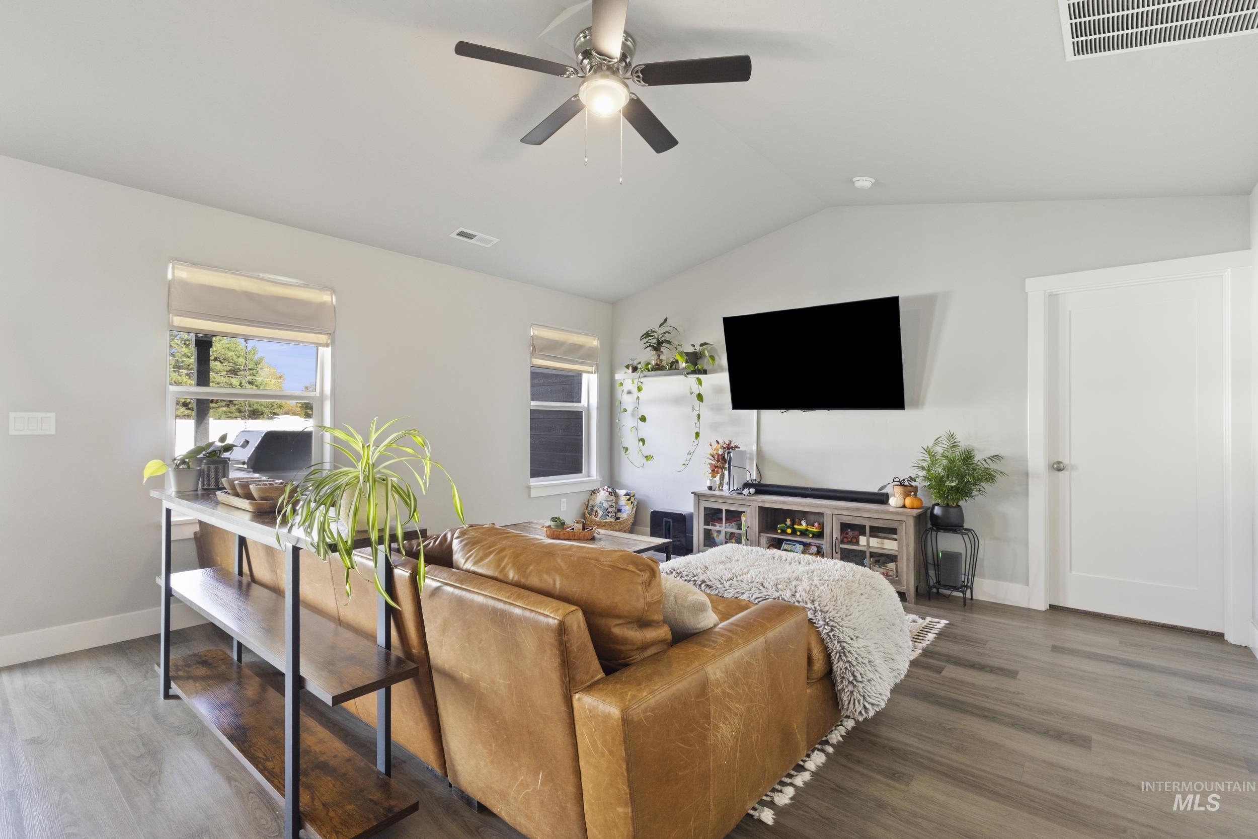 Living area with vaulted ceiling, wood finished floors, and a ceiling fan