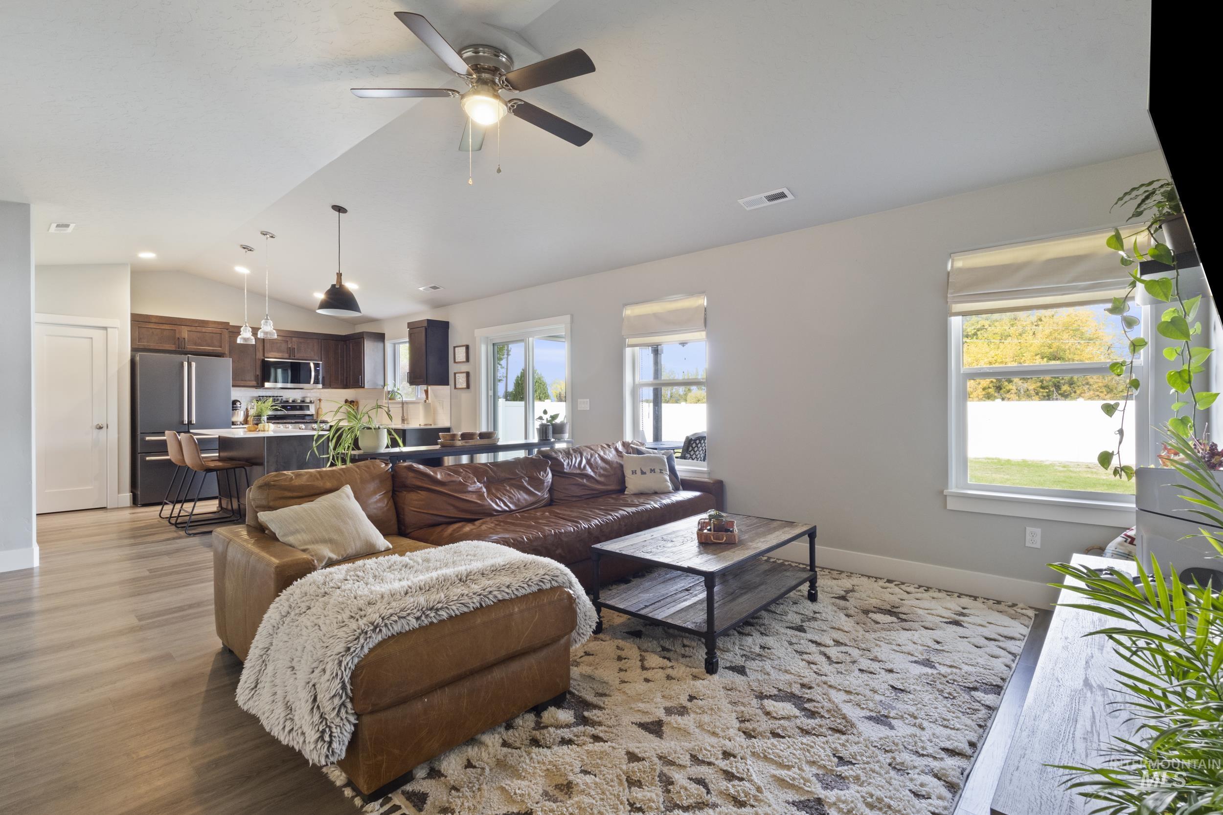 Living area featuring lofted ceiling, light wood-style flooring, and ceiling fan