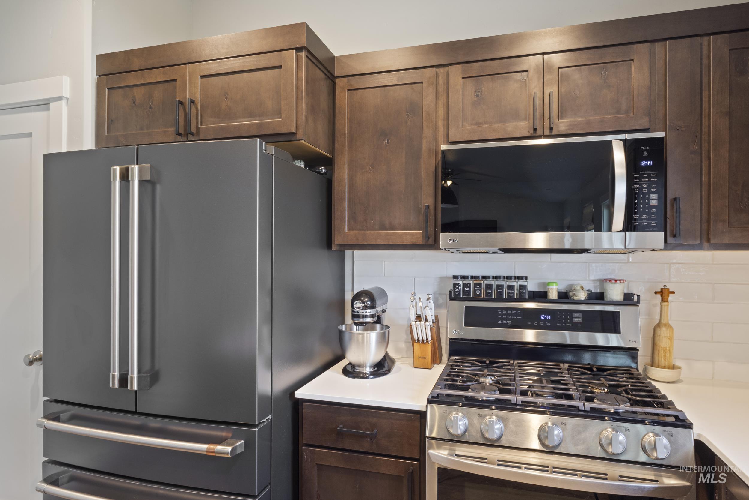 Kitchen featuring dark brown cabinetry, appliances with stainless steel finishes, and tasteful backsplash