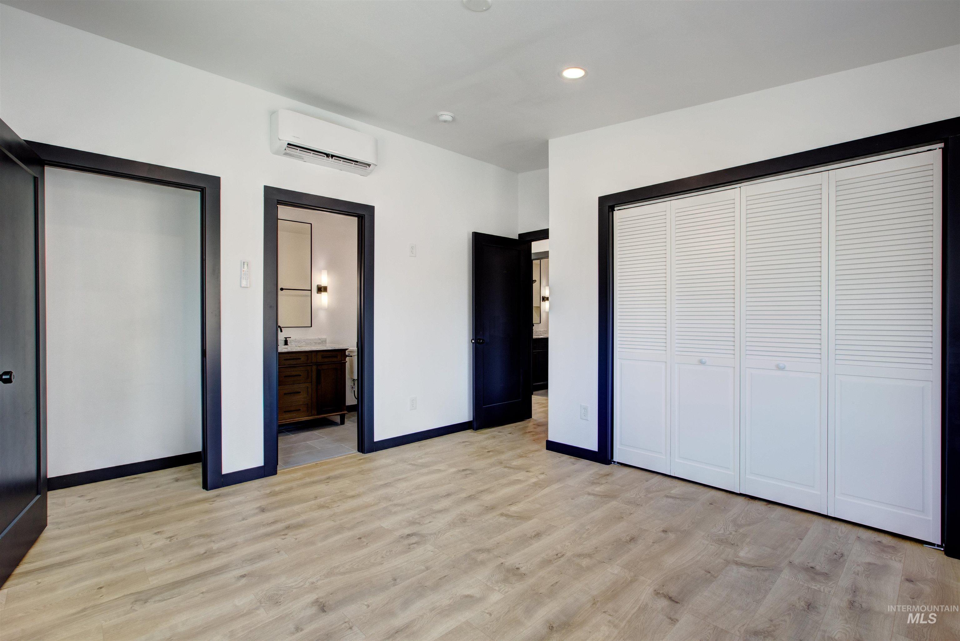 Master bedroom with light wood-type flooring, recessed lighting, a wall mounted AC, and ensuite bathroom