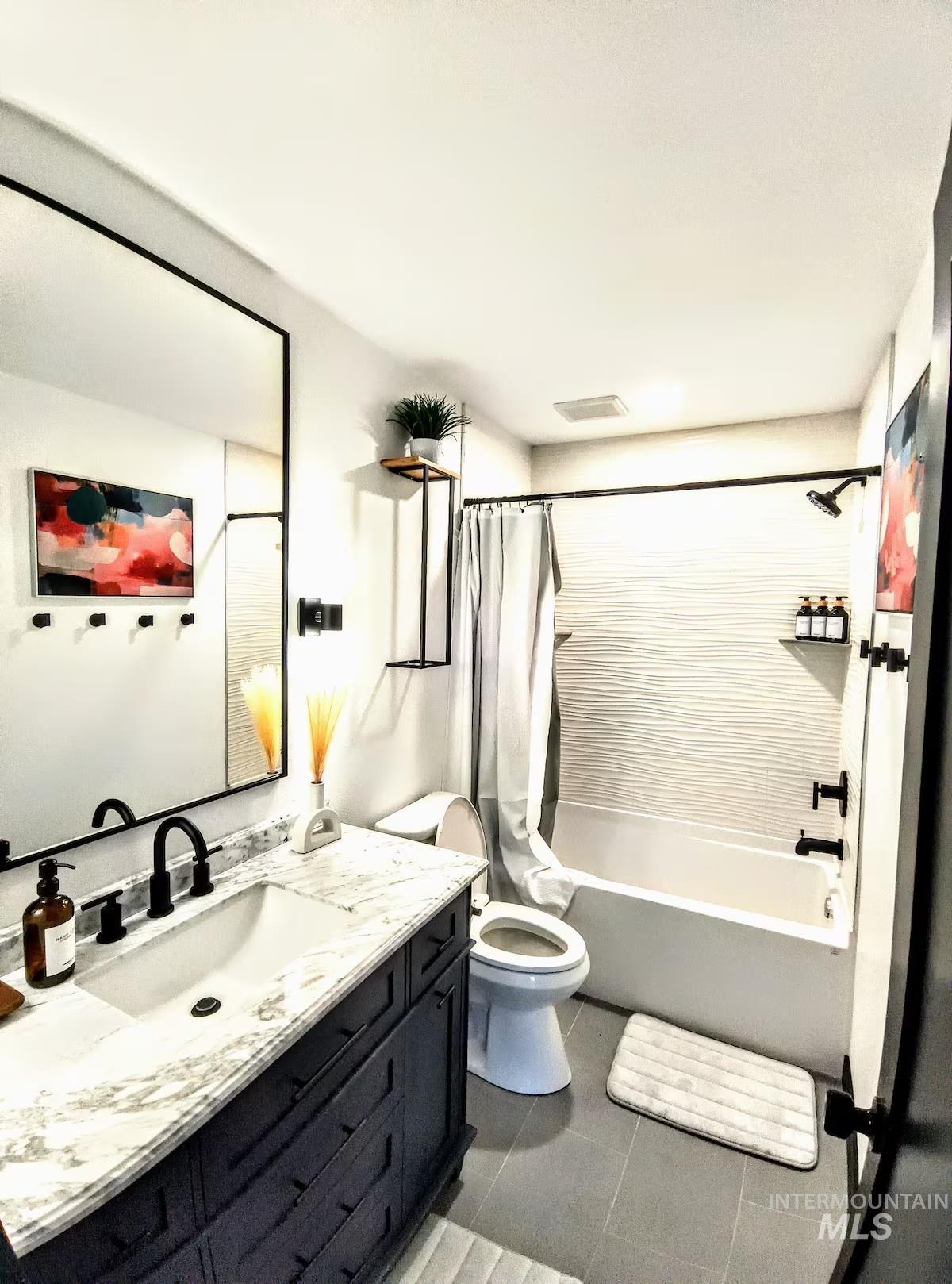 Bathroom featuring shower / bath combination with curtain, vanity, and light tile patterned floors