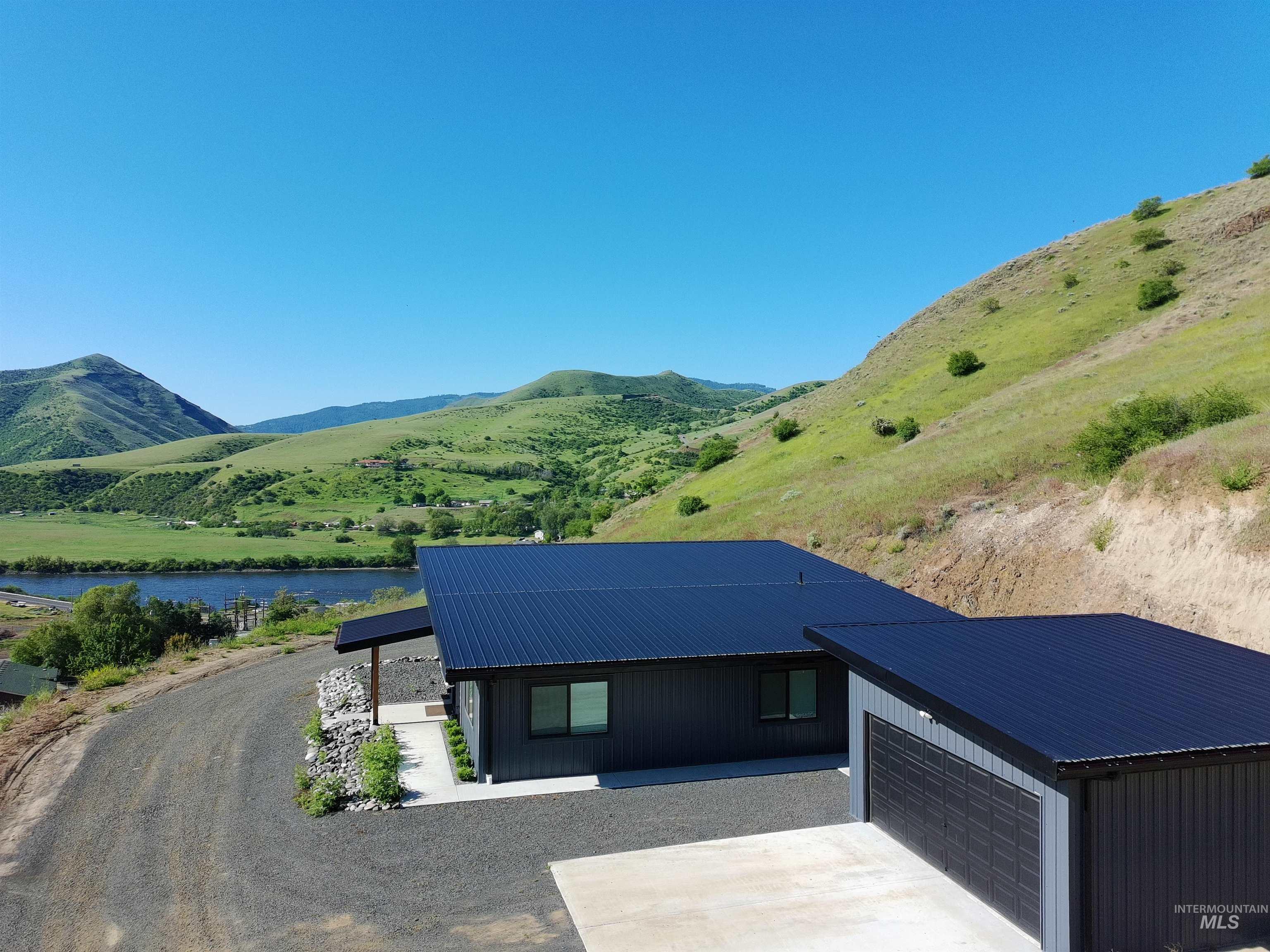 View of front of property with a metal roof, a garage, a water and mountain view, and concrete driveway