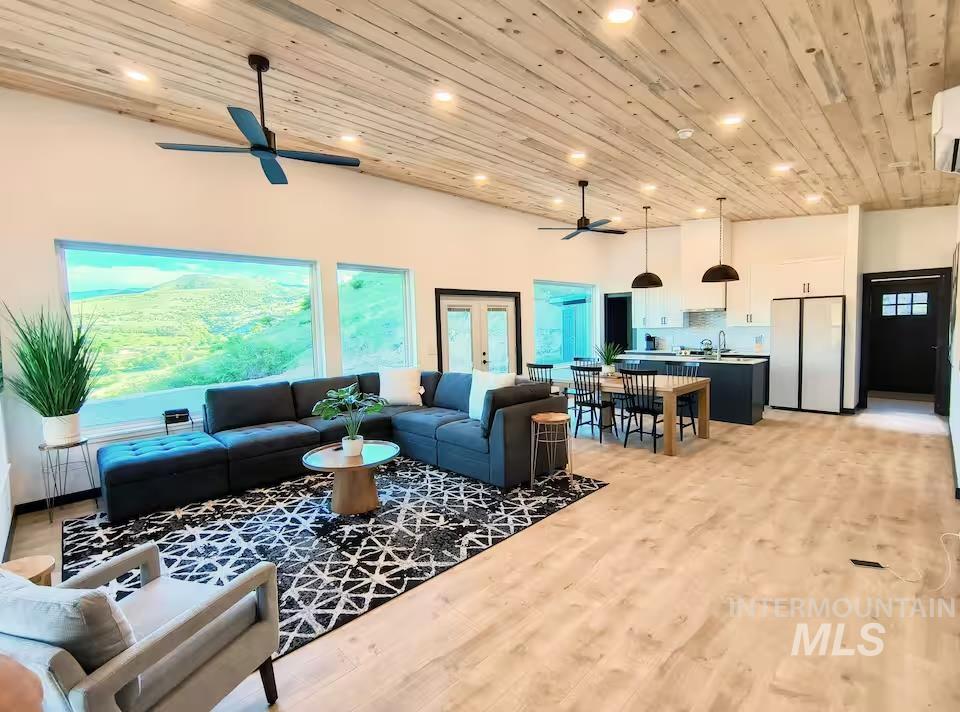 Living room featuring wooden ceiling, a towering ceiling, light wood finished floors, recessed lighting, and ceiling fan