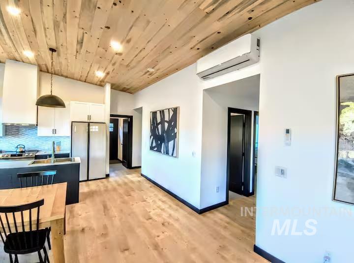 Kitchen featuring white cabinetry, pendant lighting, tasteful backsplash, light wood-style flooring, and wood ceiling