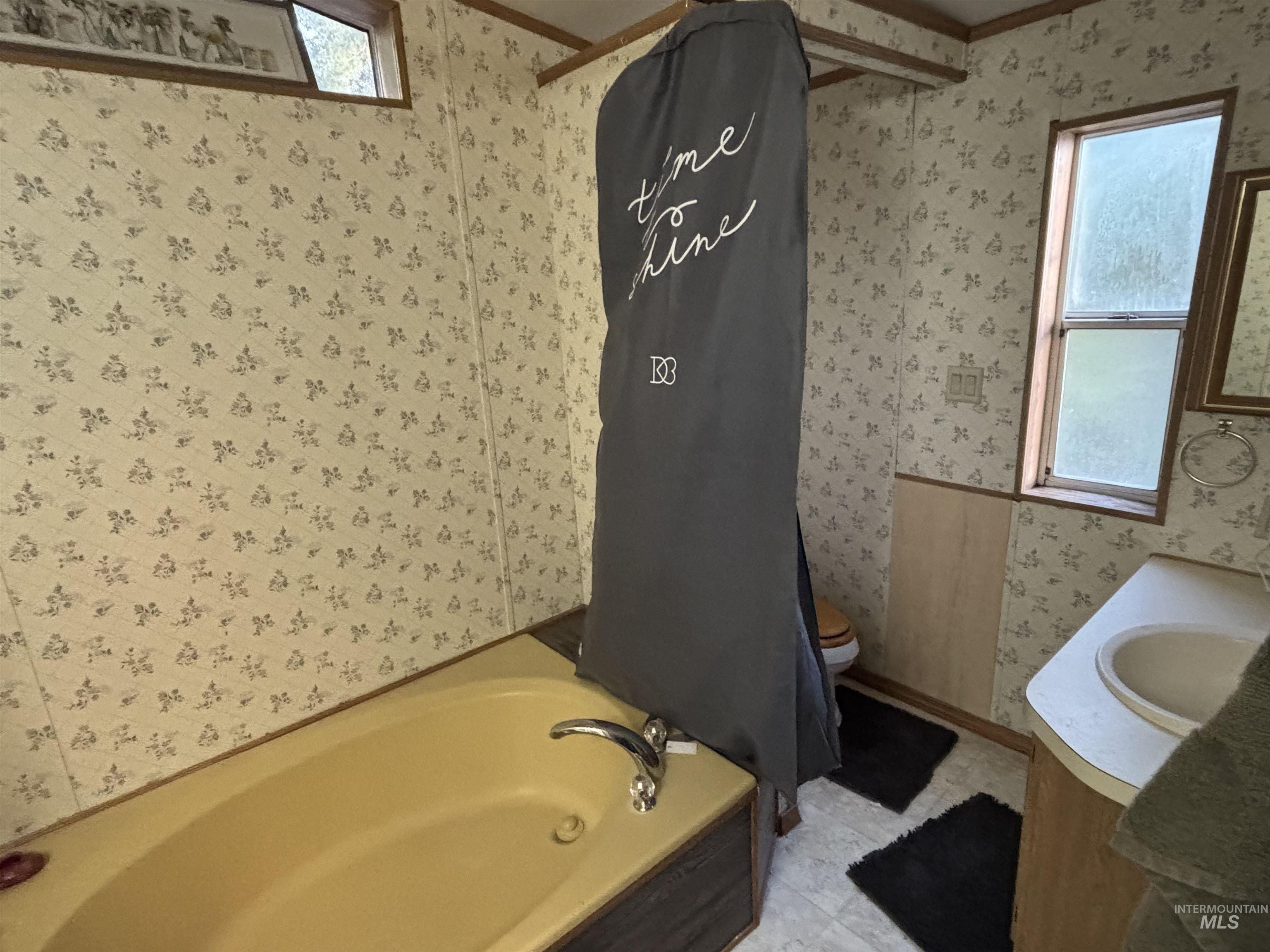 Bathroom with wallpapered walls and vanity
