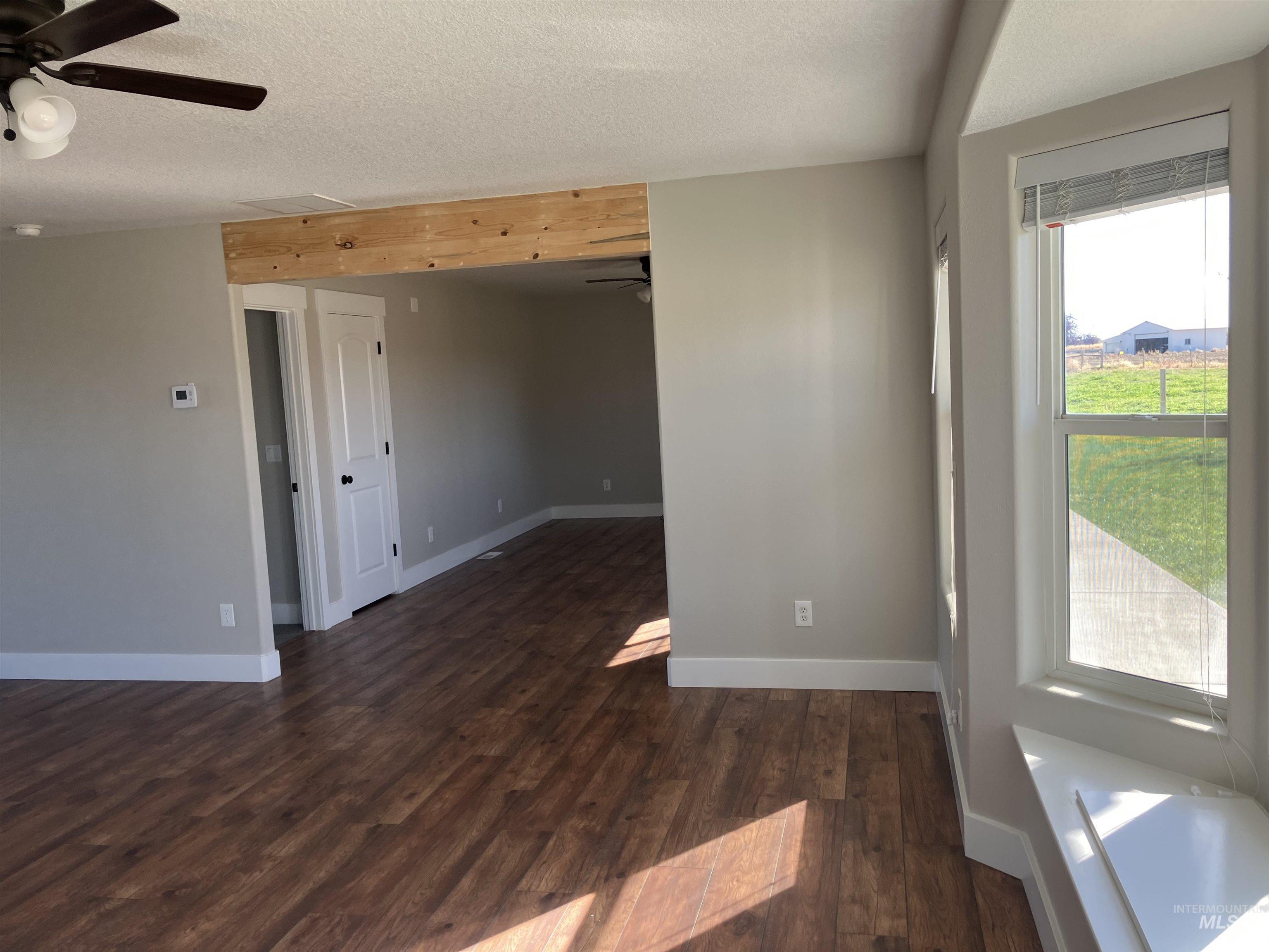 Unfurnished room featuring dark wood-style flooring, ceiling fan, and a textured ceiling