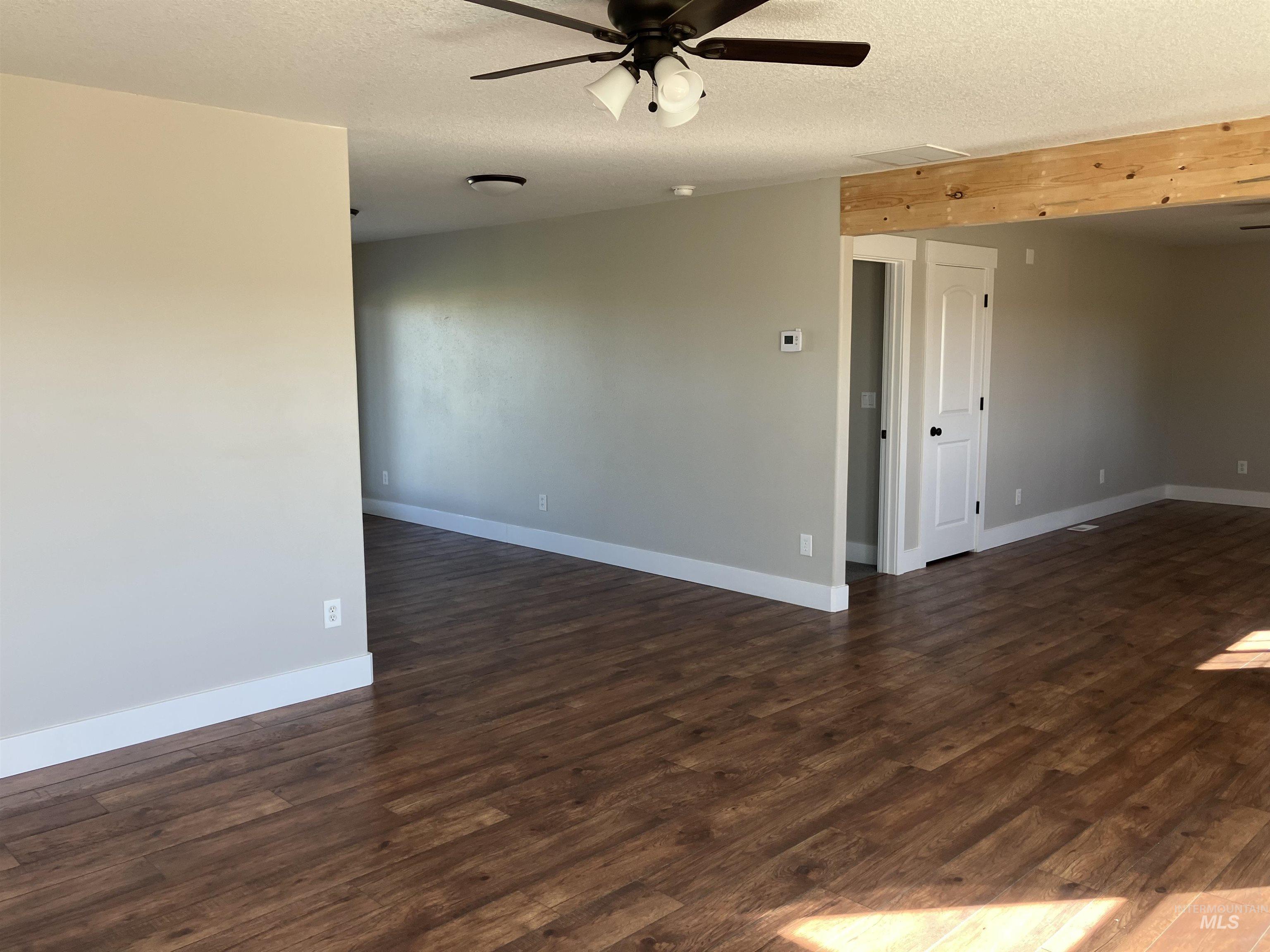 Unfurnished room with dark wood finished floors, a textured ceiling, and a ceiling fan