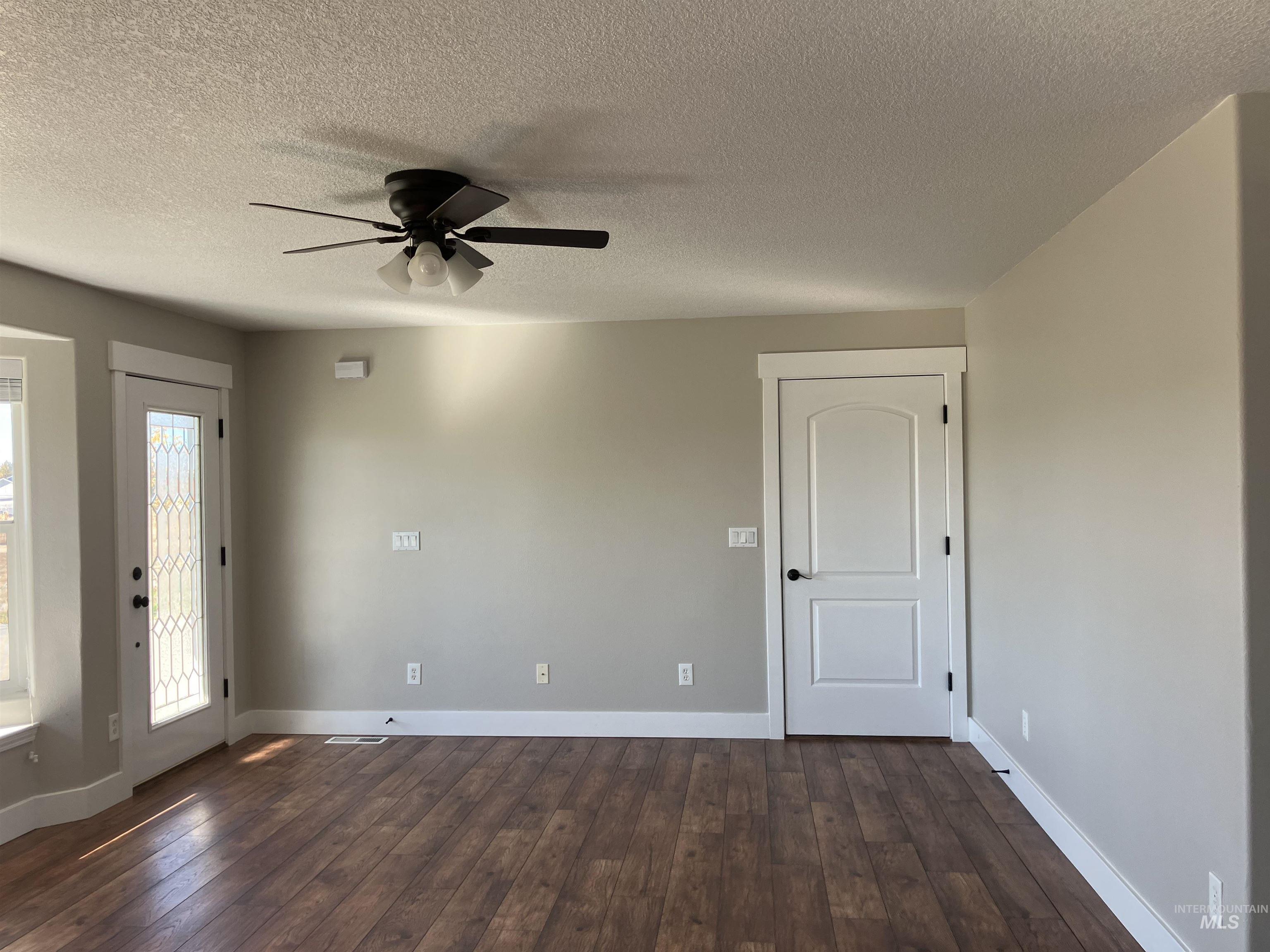 Unfurnished room with a textured ceiling, dark wood-style floors, and ceiling fan